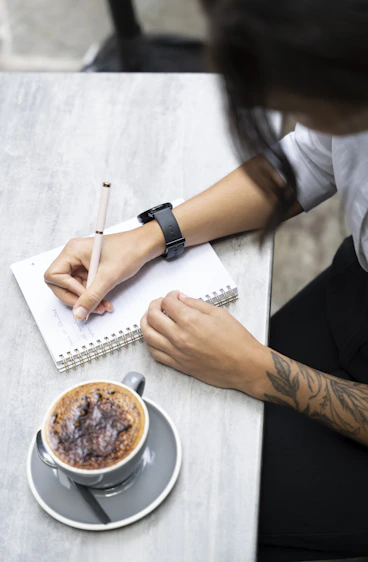 A person sitting at a table with a cup of coffee