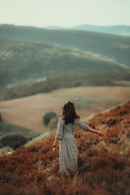 A woman standing on top of a lush green hillside