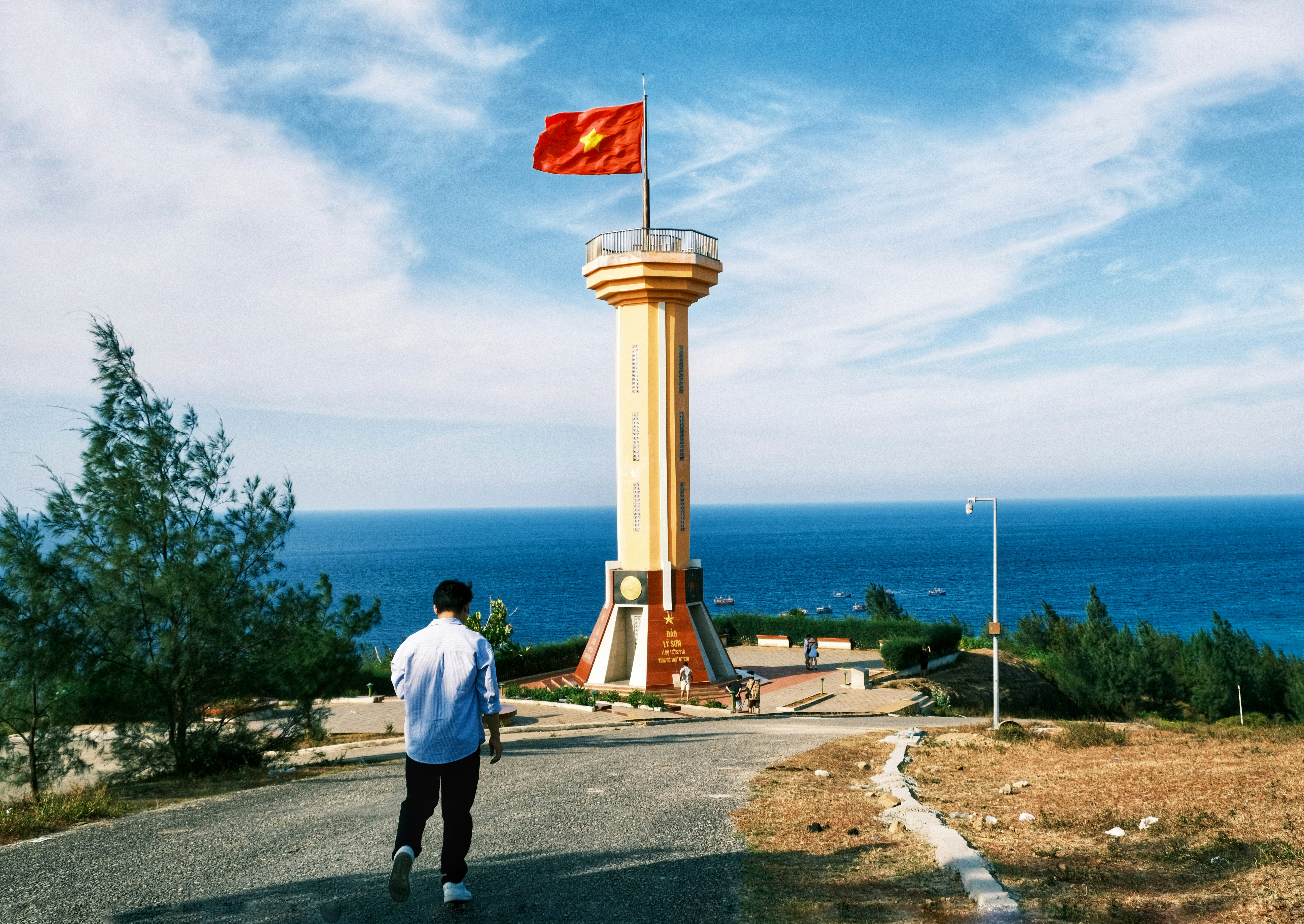 A man walking down a road towards a tall tower