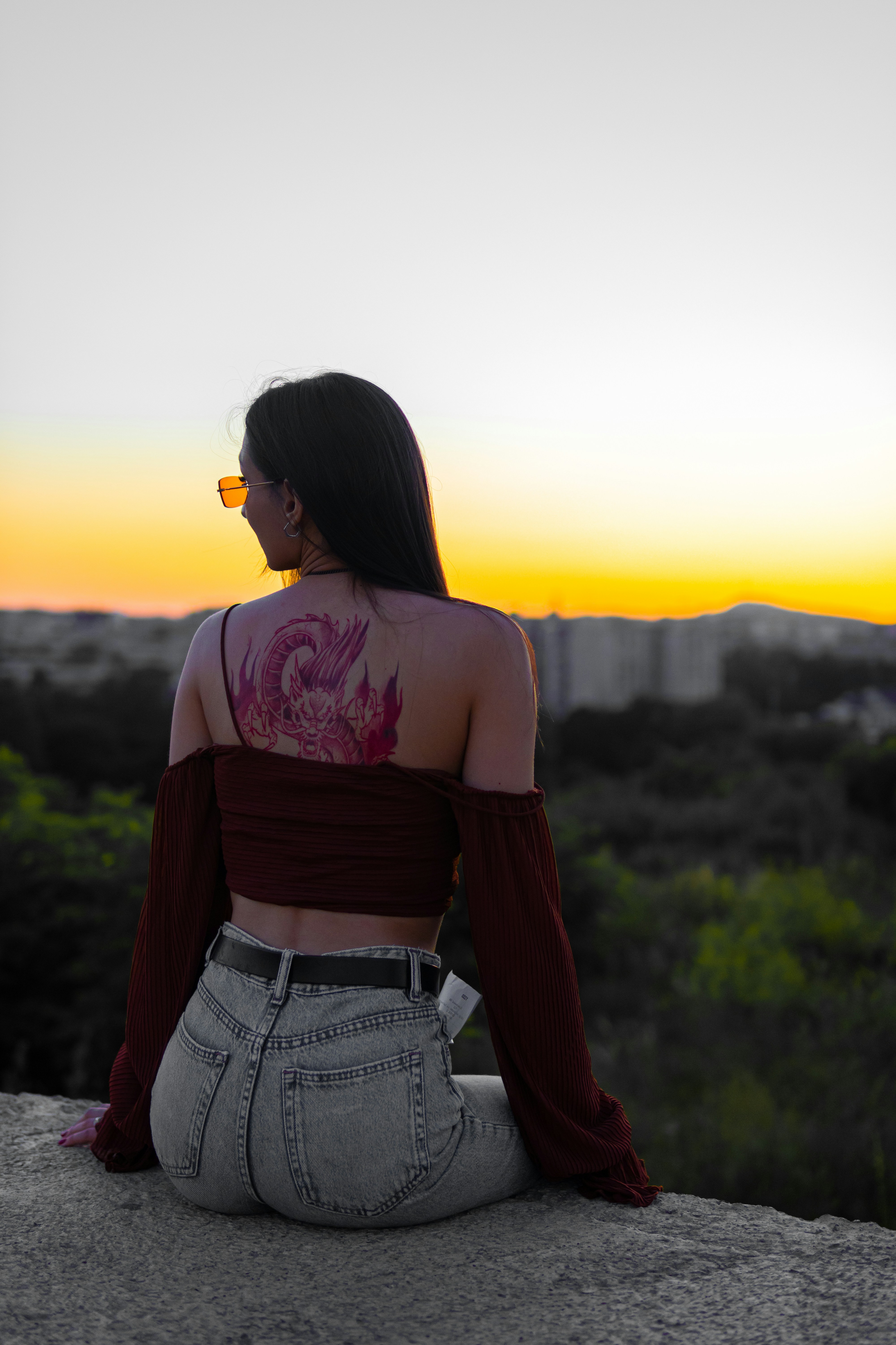 A woman sitting on a rock looking at the sunset