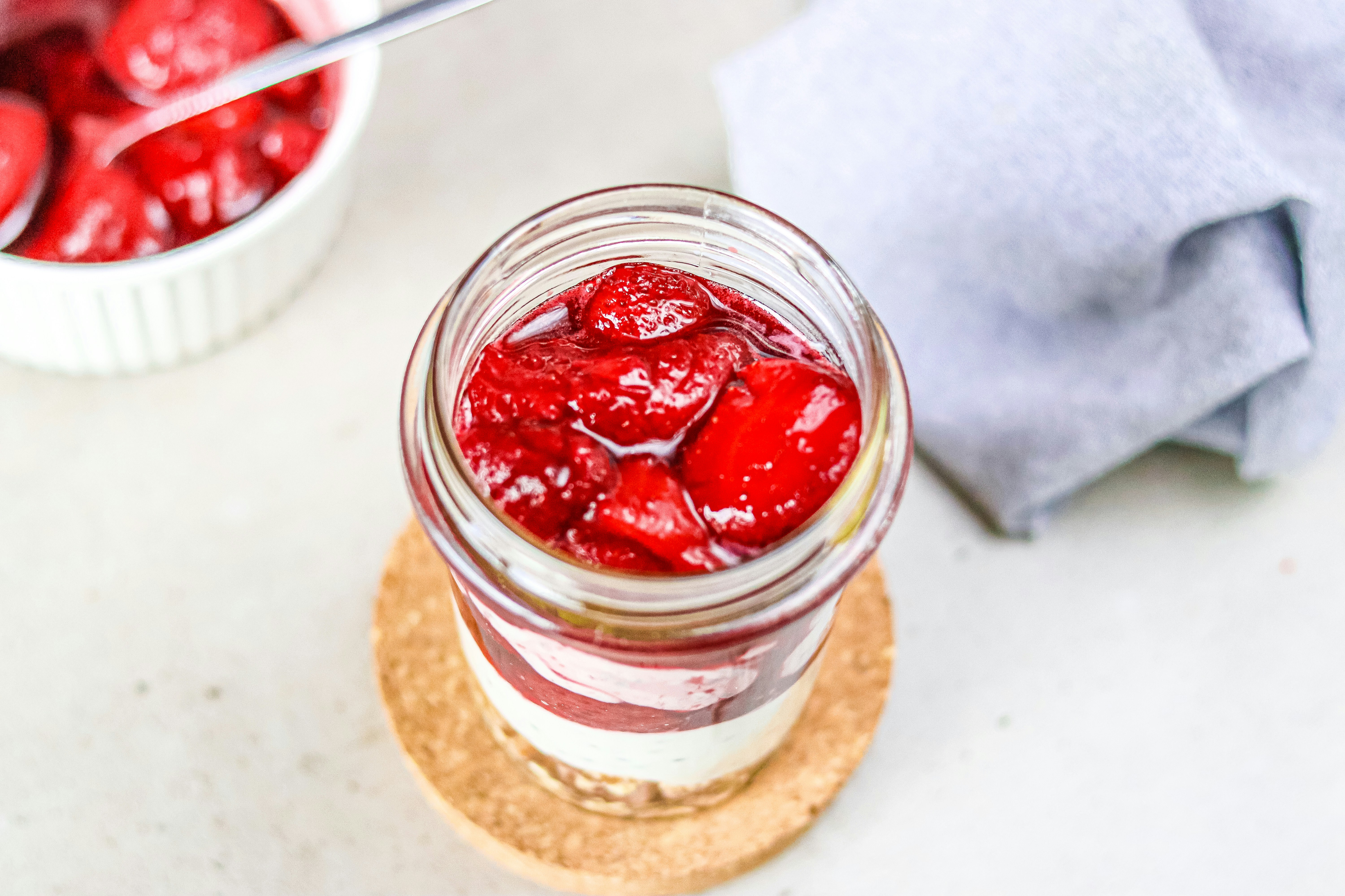 A jar of strawberry jam sitting on top of a cork coaster