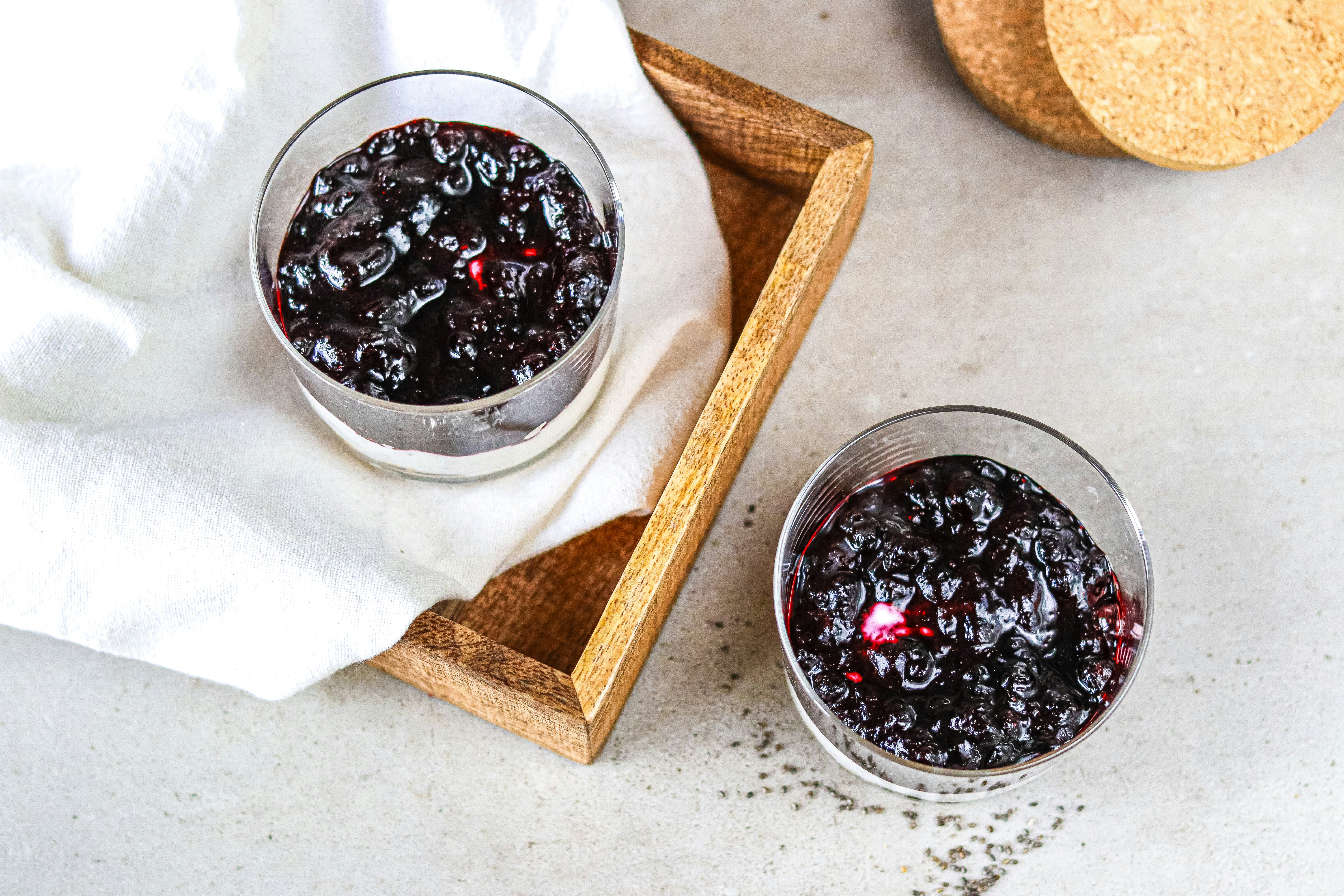 Two glasses of blueberry compote on a wooden tray