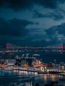 A view of a city at night with a bridge in the background