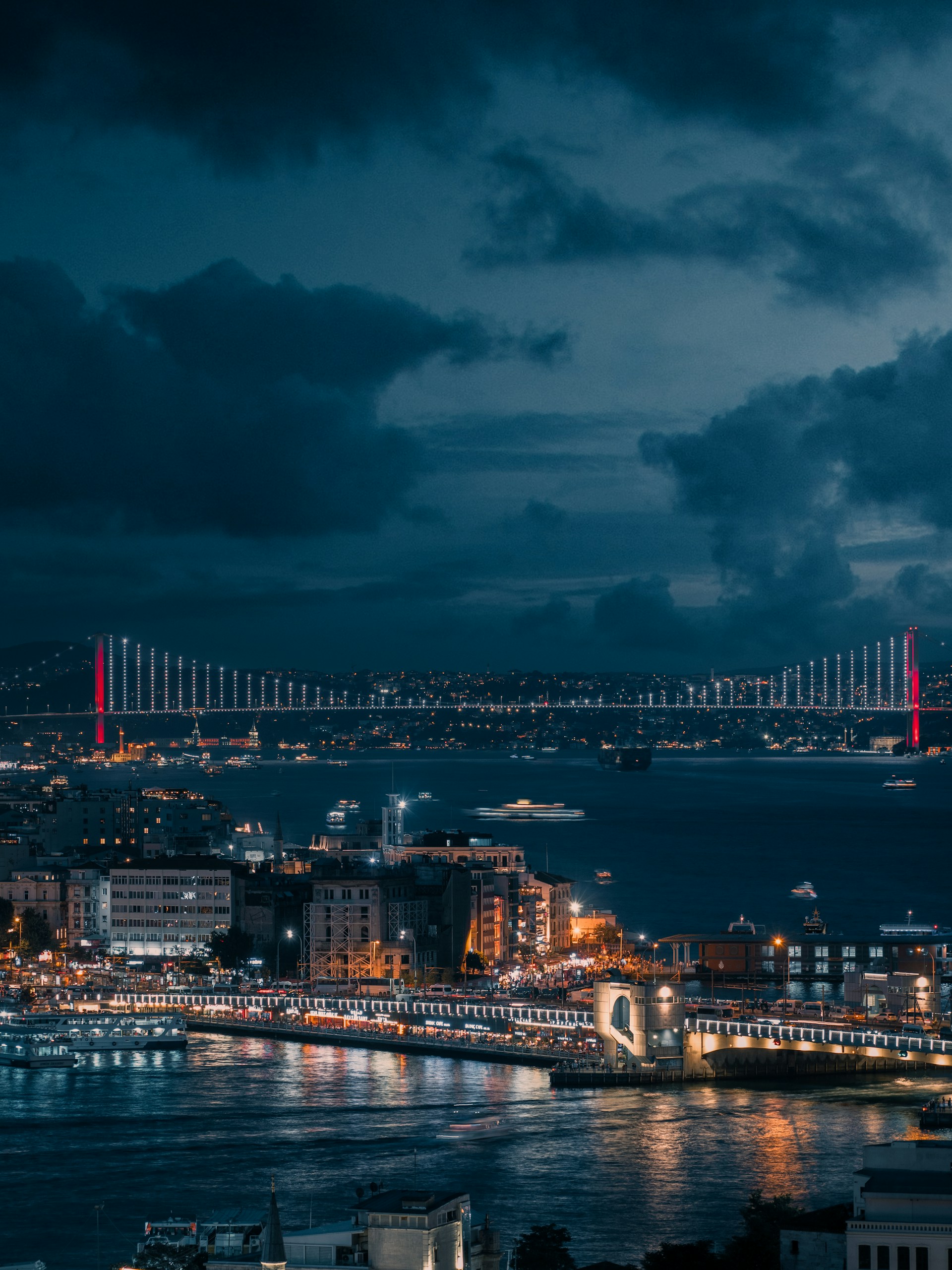 A view of a city at night with a bridge in the background