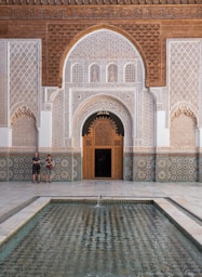 Two people standing in front of a building with a fountain