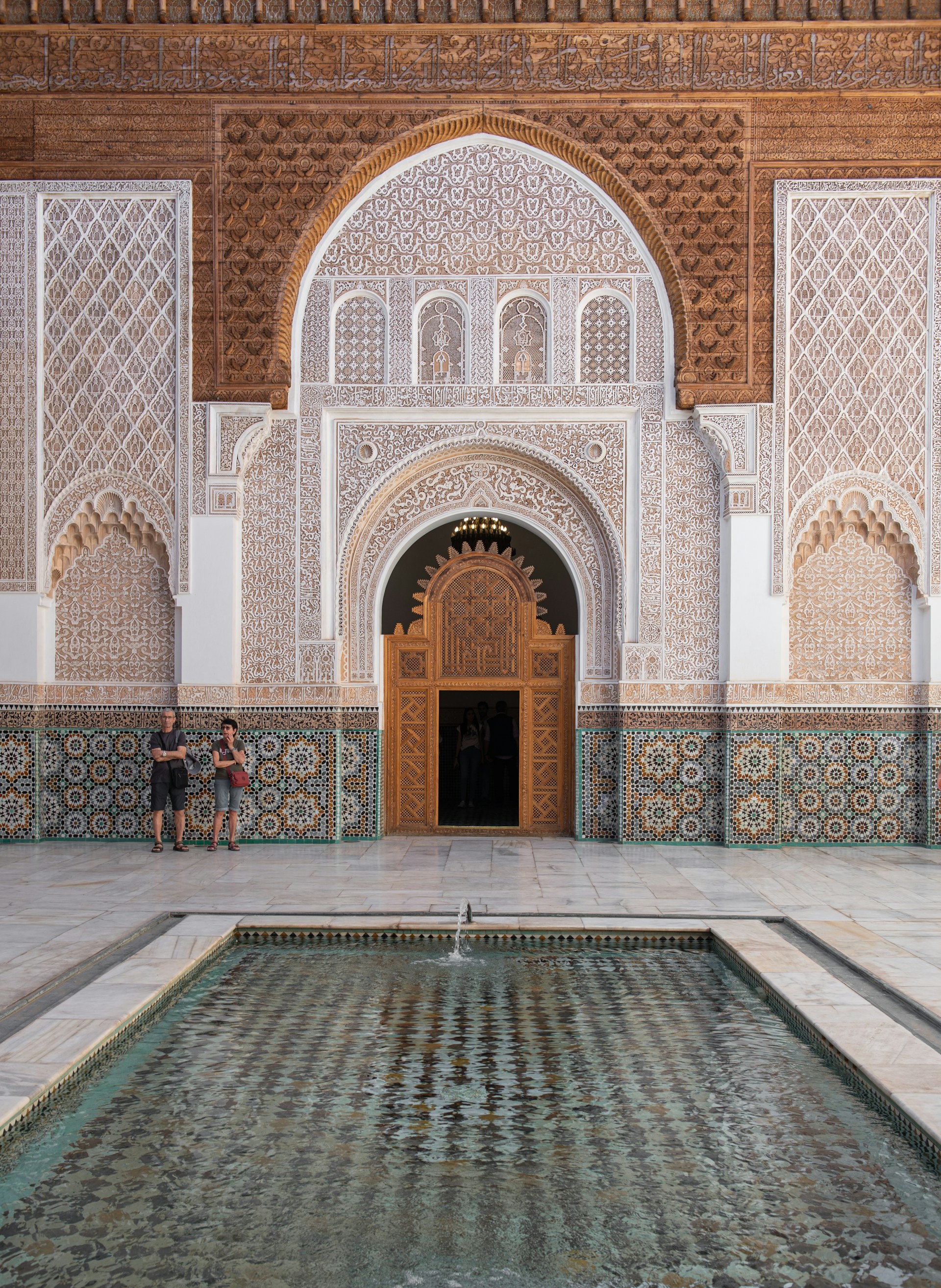 Two people standing in front of a building with a fountain