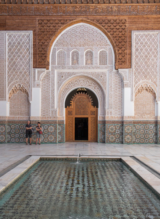 Two people standing in front of a building with a fountain