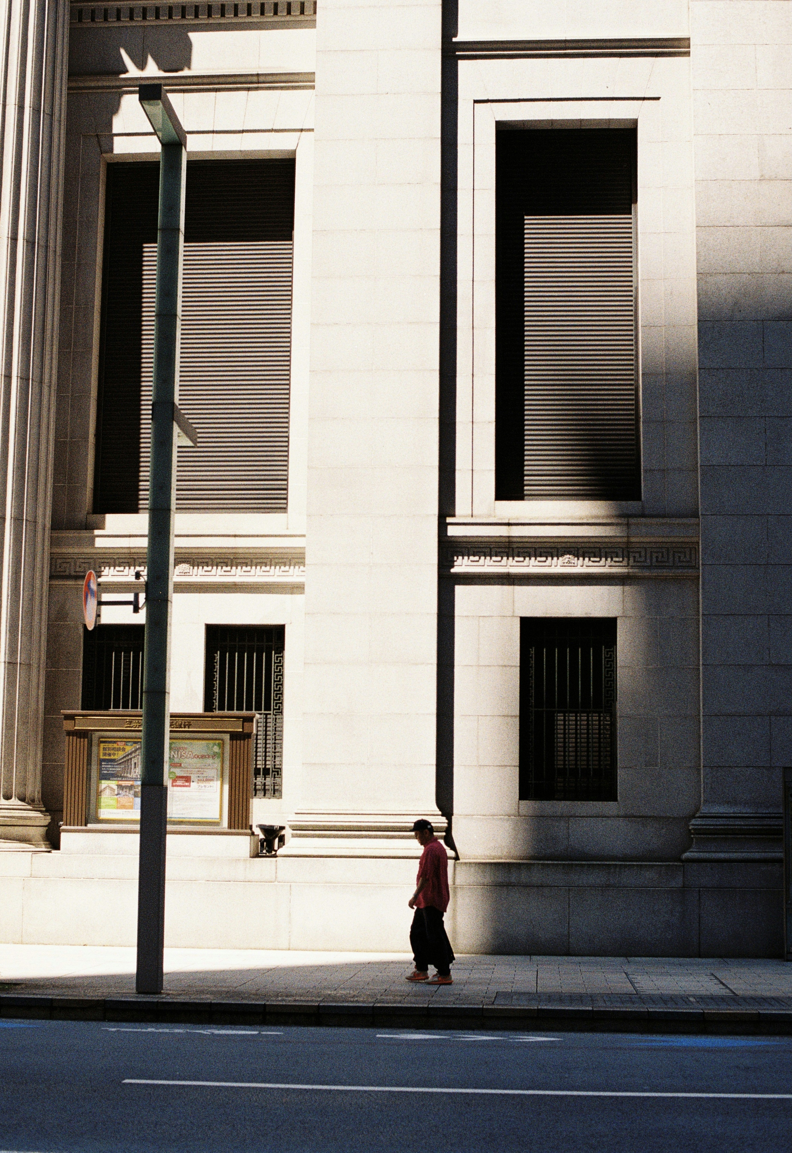 A person walking down a street past a tall building