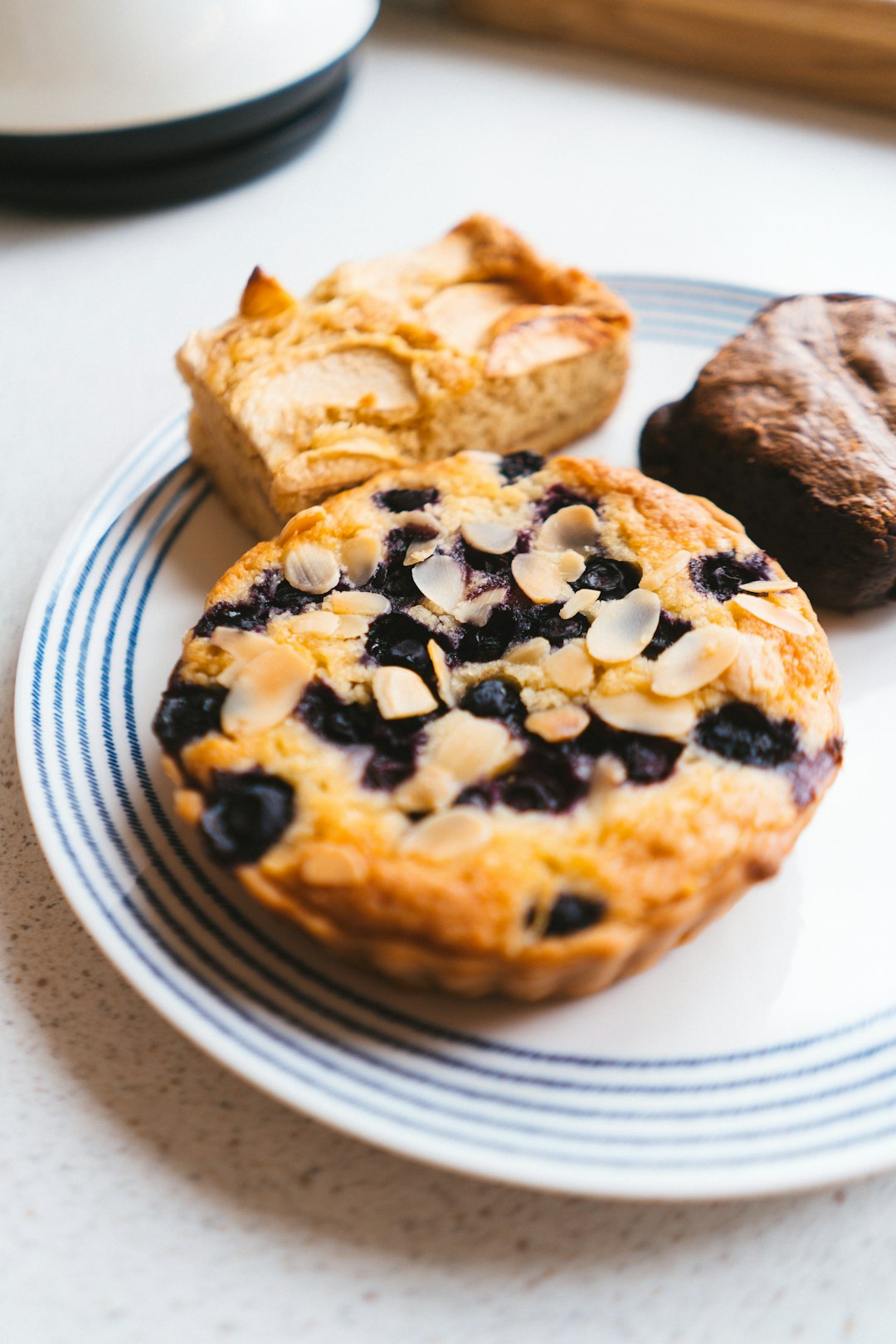 A white plate topped with blueberry muffins next to a cup of coffee