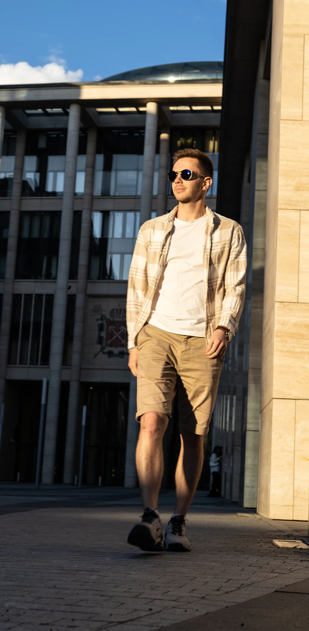 A man walking down a sidewalk in front of a building