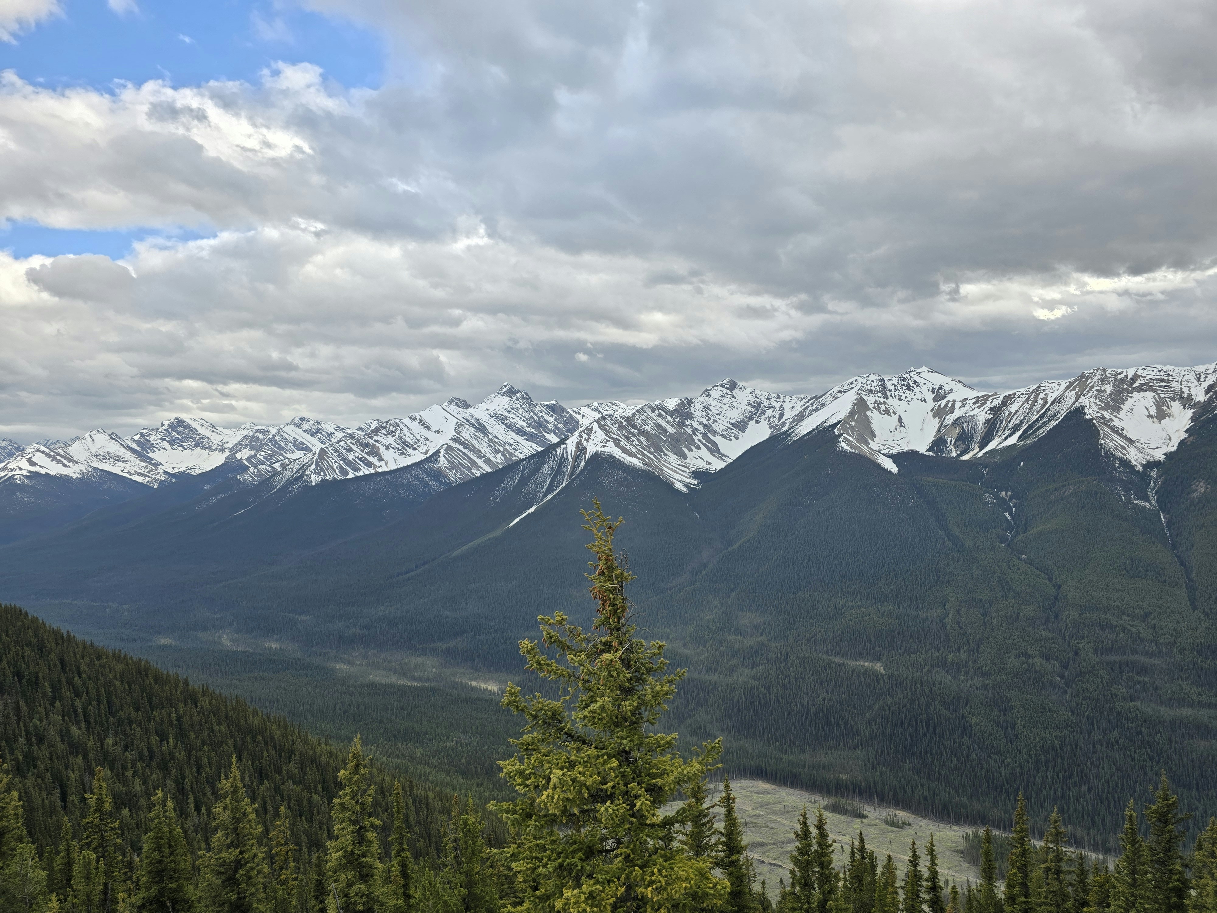 A view of a mountain range with snow capped mountains in the distance