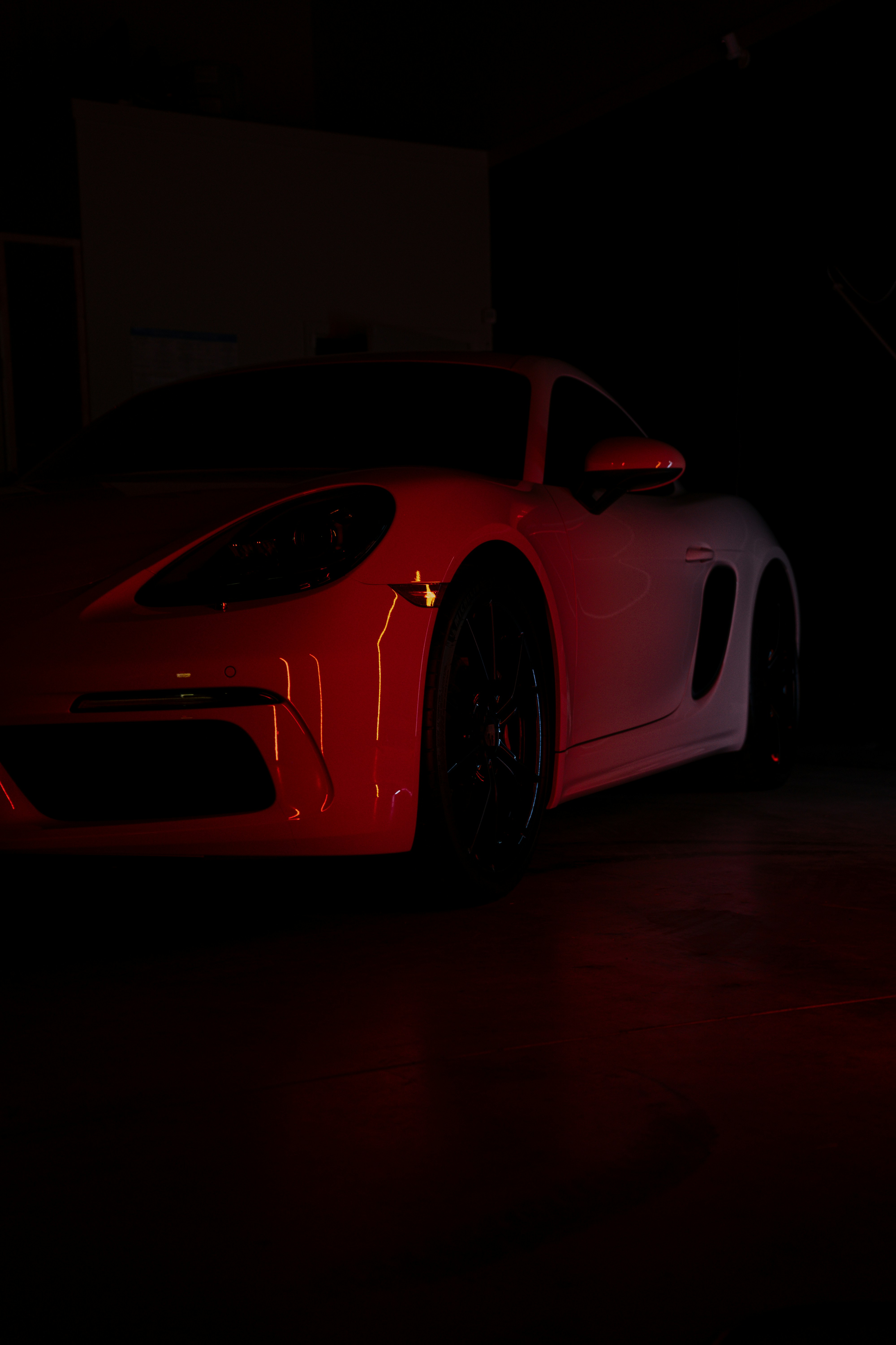 A red sports car parked in a dark garage