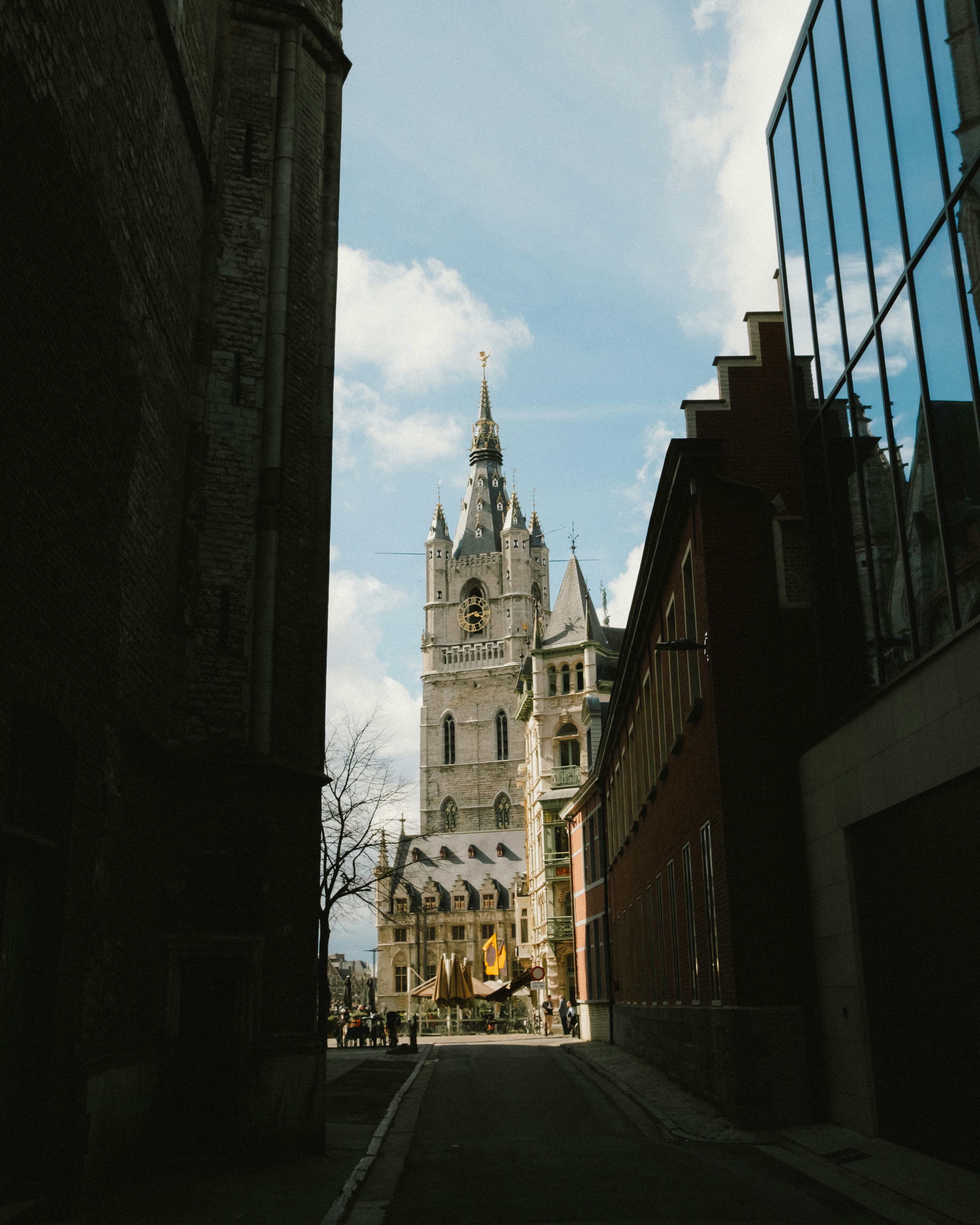 A narrow city street with a church steeple in the background