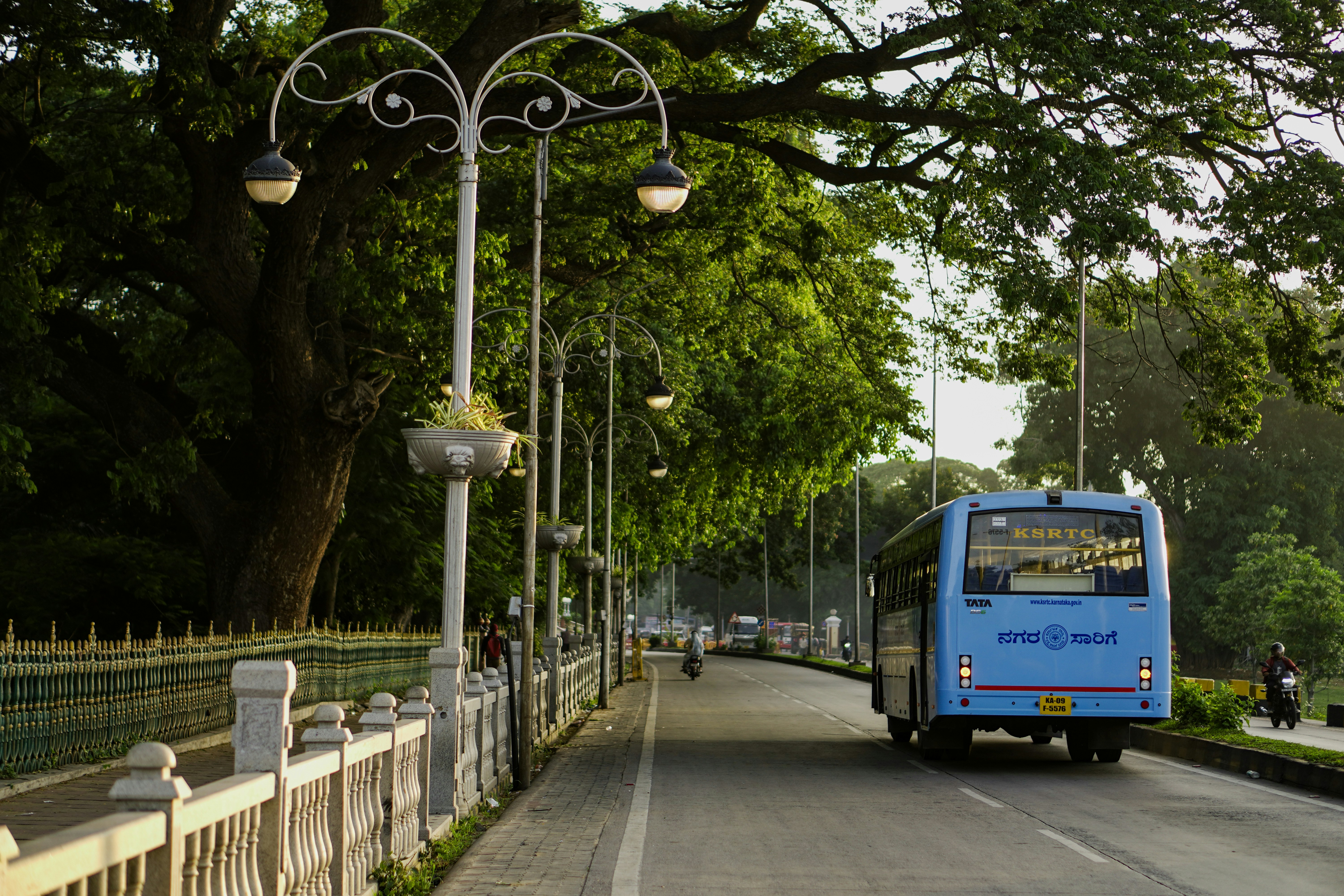 A blue bus driving down a street next to a fence