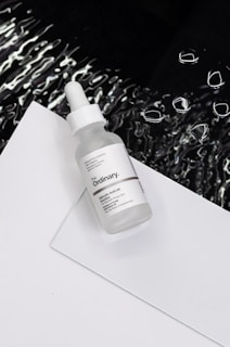 A white bottle of liquid sitting on top of a white piece of paper