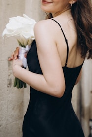 A woman in a black dress holding a bouquet of flowers