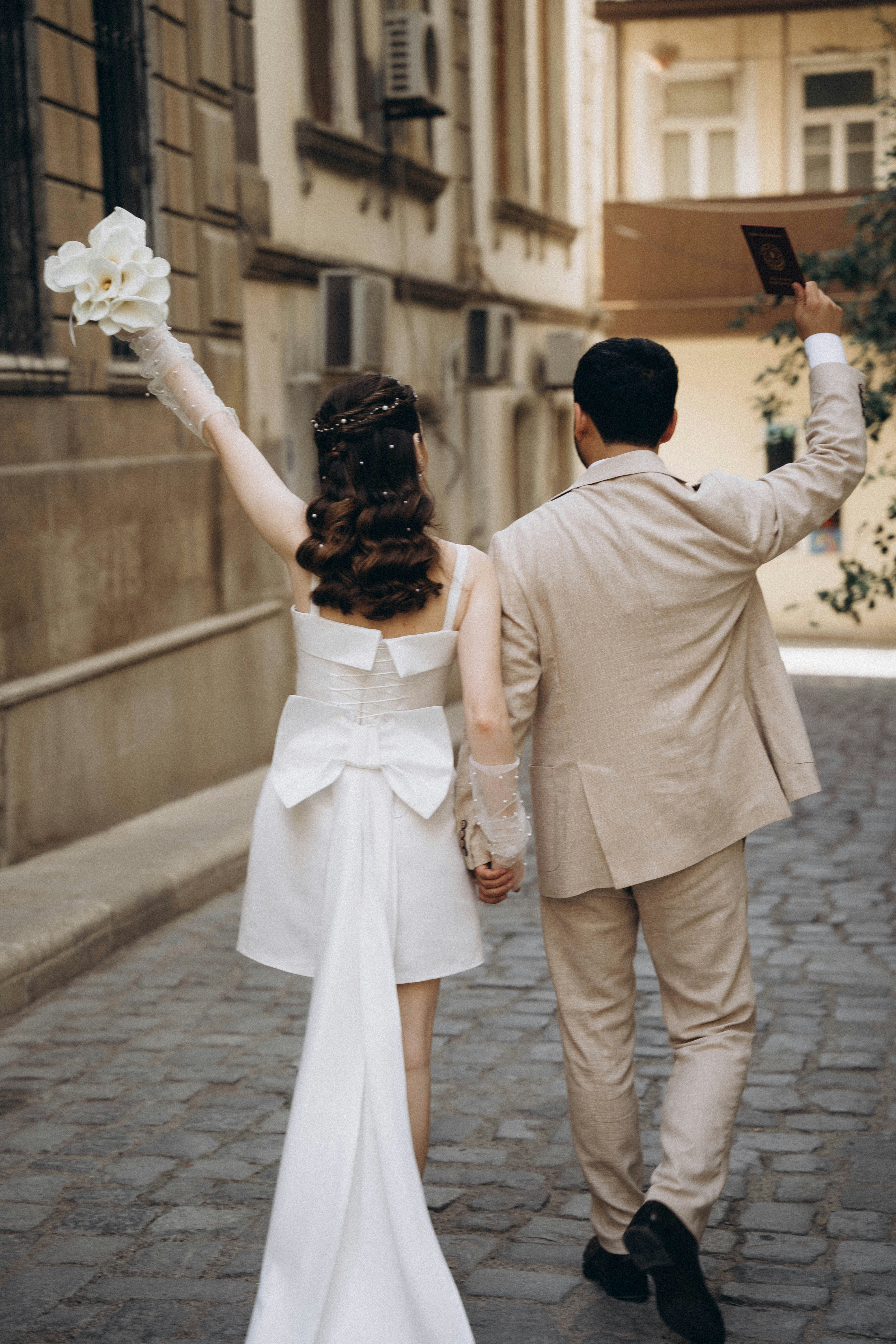 A bride and groom walking down a cobblestone street