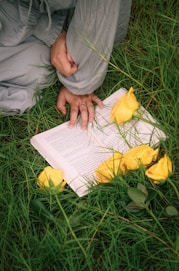 A person sitting in the grass reading a book