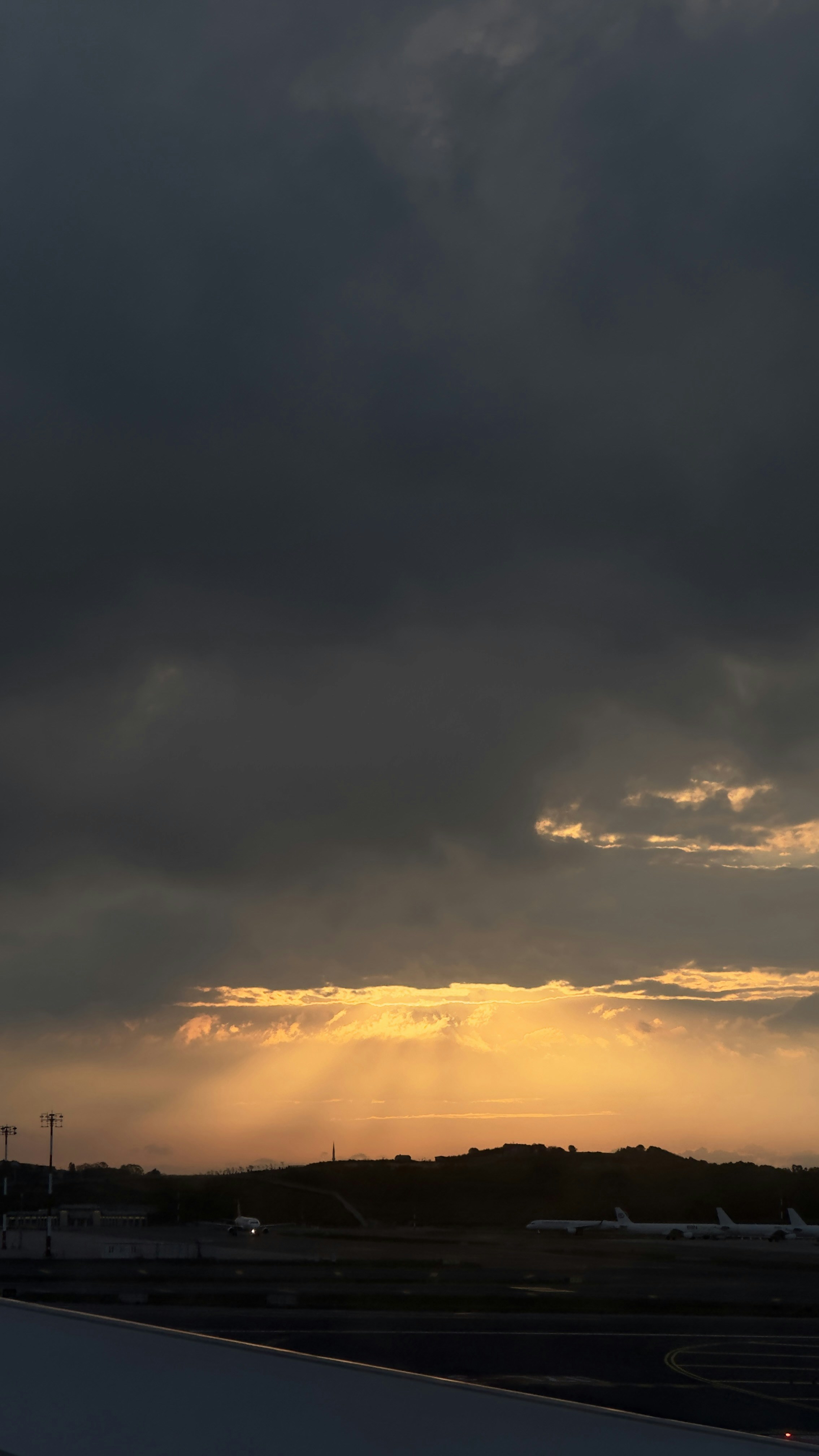 Commercial aircraft on runway at dusk, dark dramatic sky, takeoff position, atmospheric low light