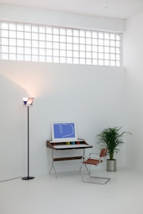 A white room with a computer and a plant