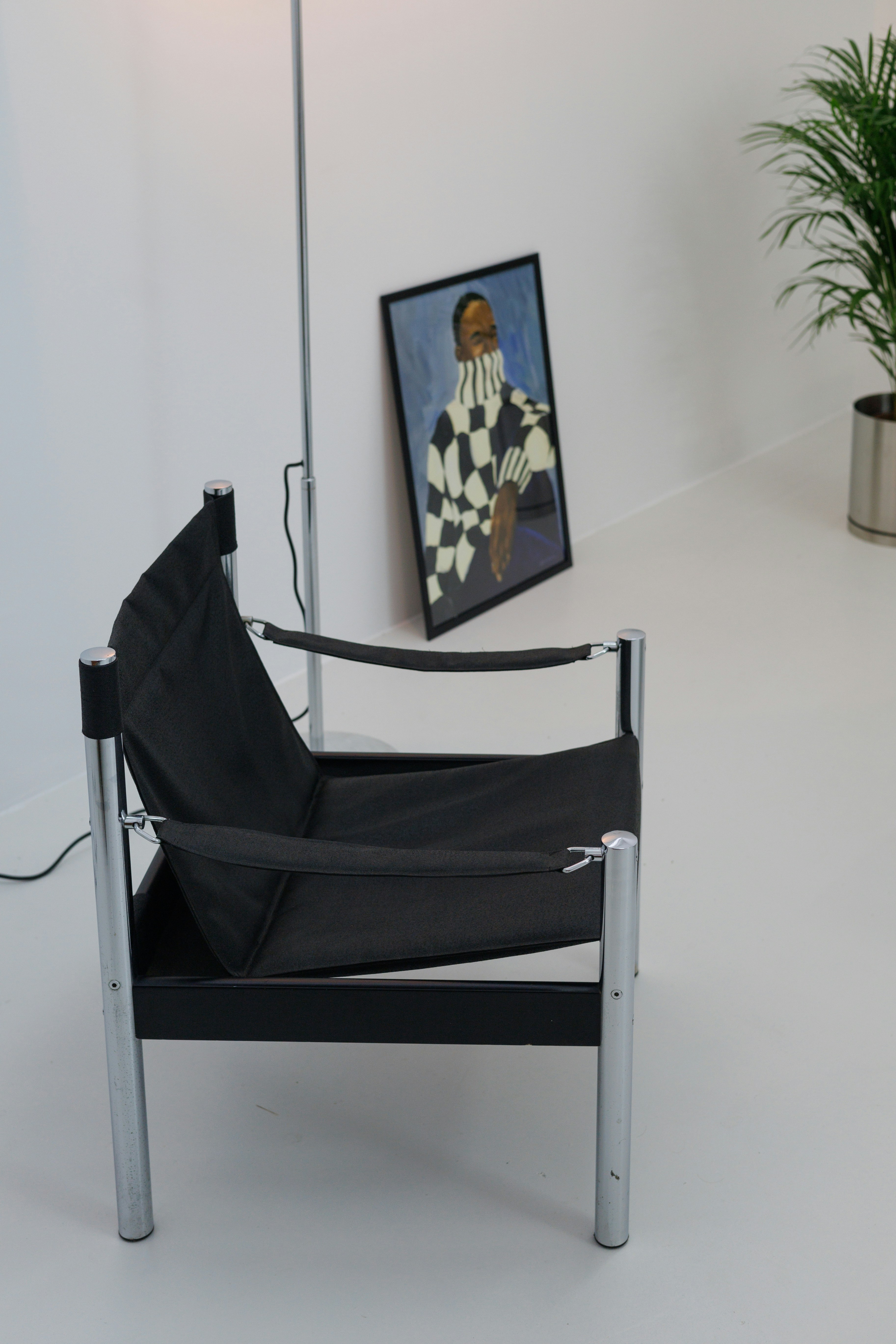 A black chair sitting in a room next to a painting