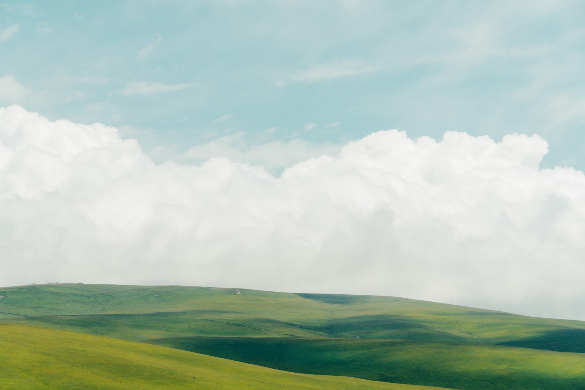 A green field with clouds in the sky