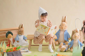 A little girl sitting on a bench reading a book