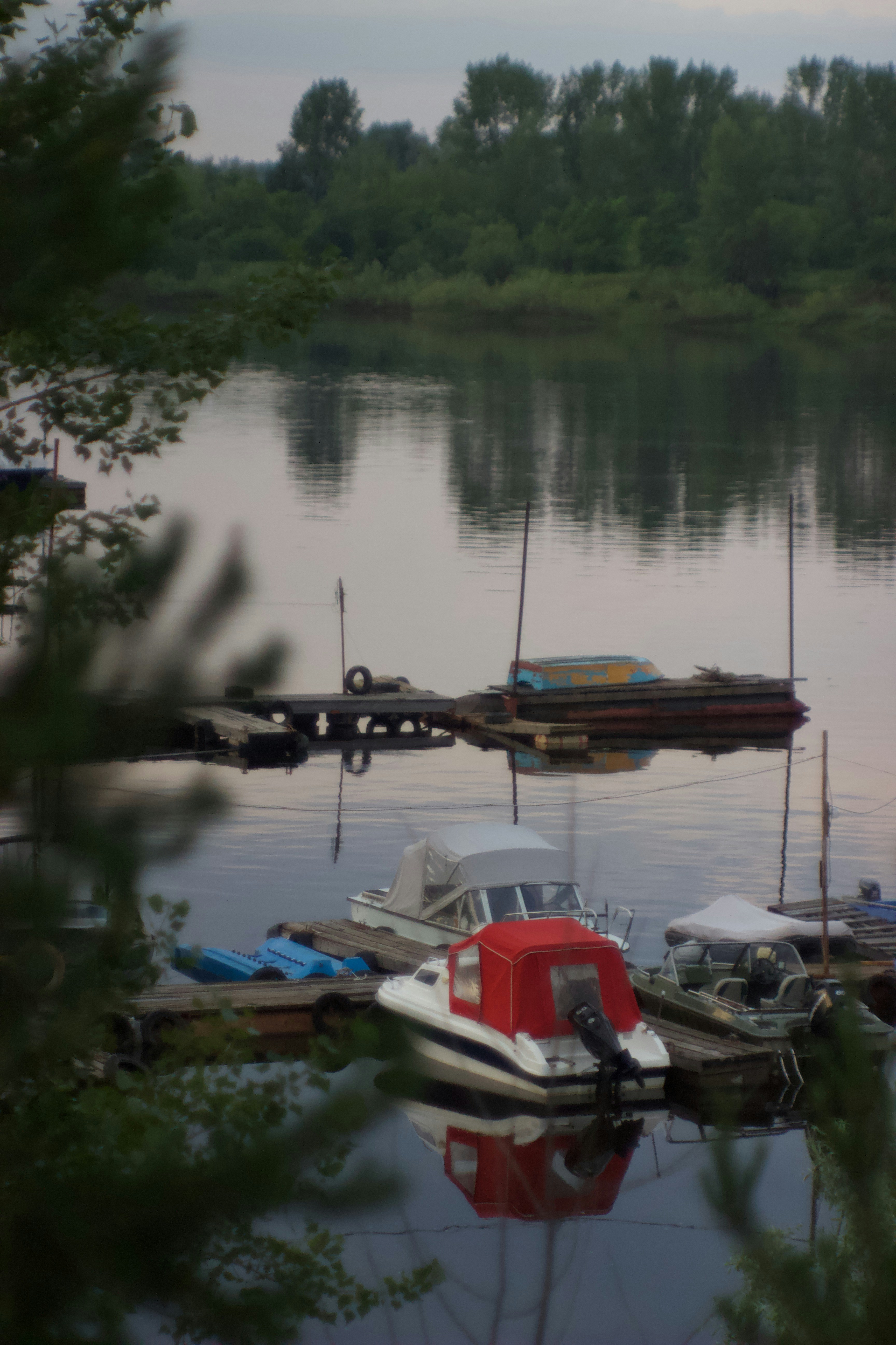 Яркие лодки на тихой реке с красочными отражениями на водной глади.