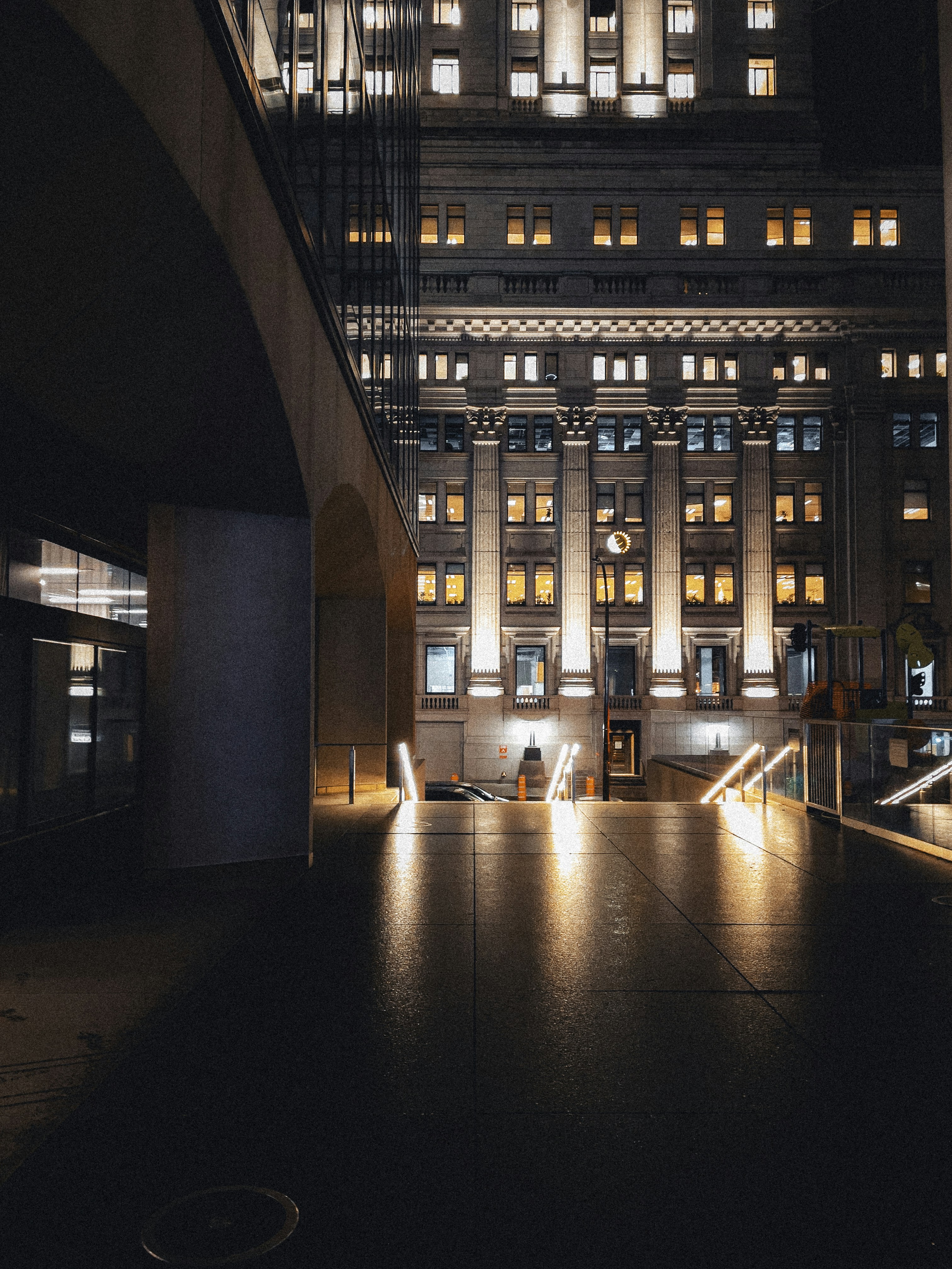 Contemporary Tokyo architecture at night with illuminated glass facades reflecting city lights on wet pavement