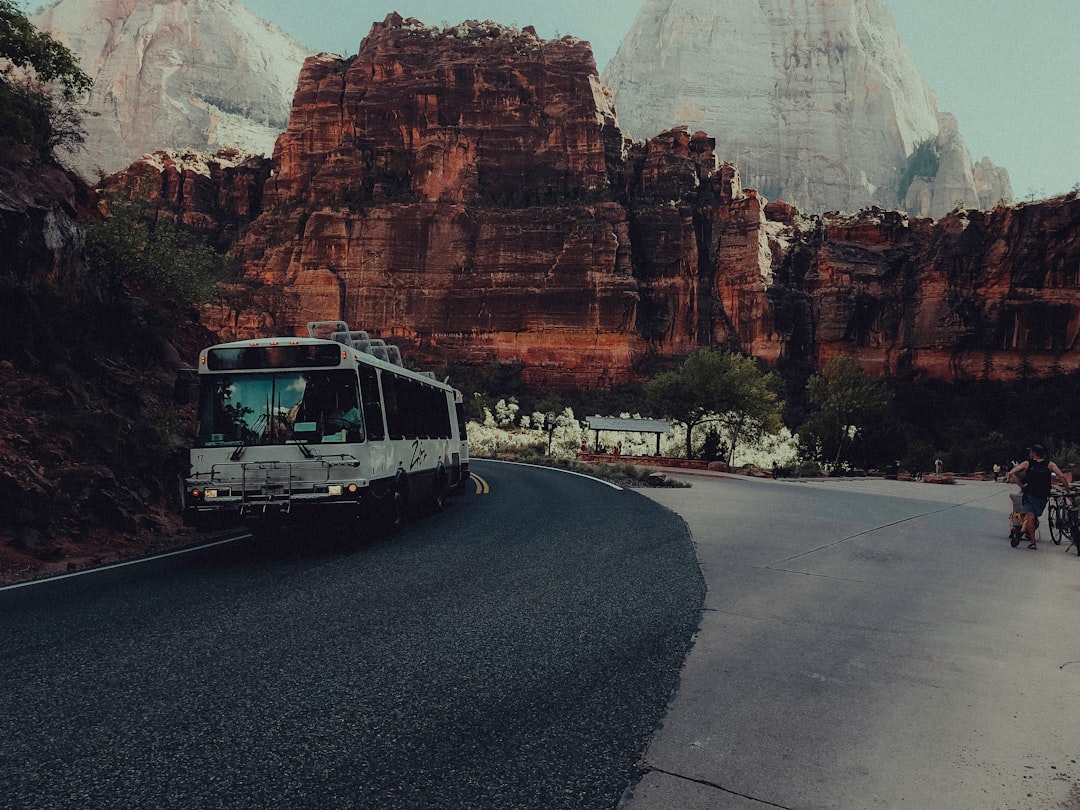 A bus driving down a road next to mountains,