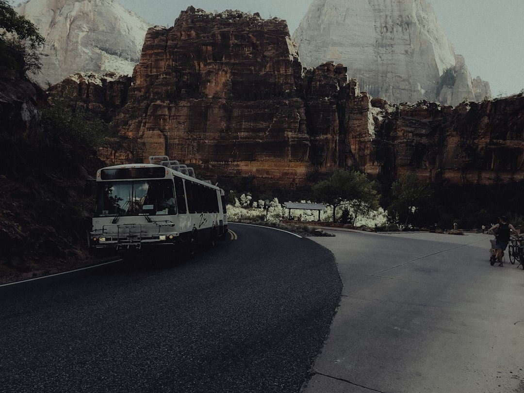 A bus driving down a road next to mountains,