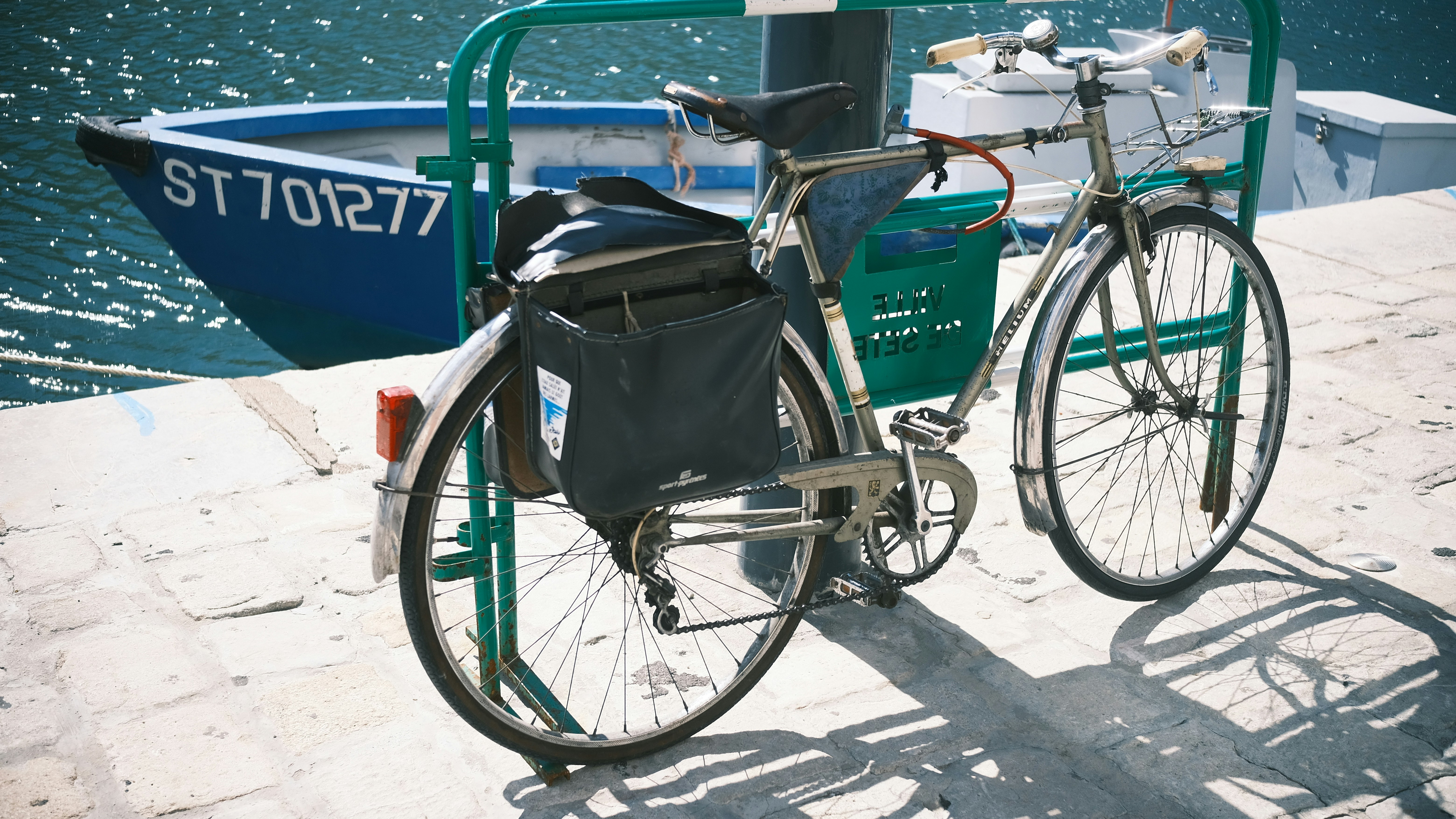 A bicycle parked next to a boat on a body of water