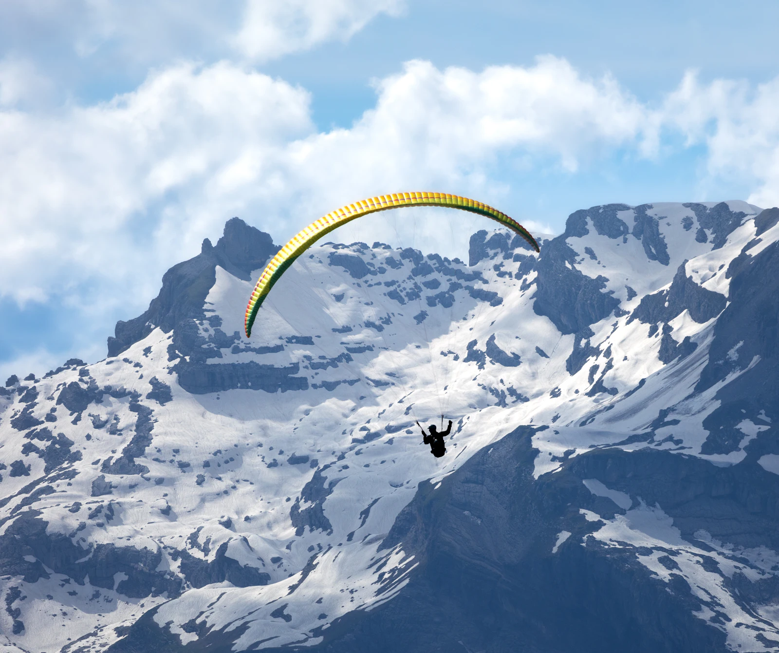Parapente en vol devant les sommets enneigés du massif du Mont-Blanc à Chamonix