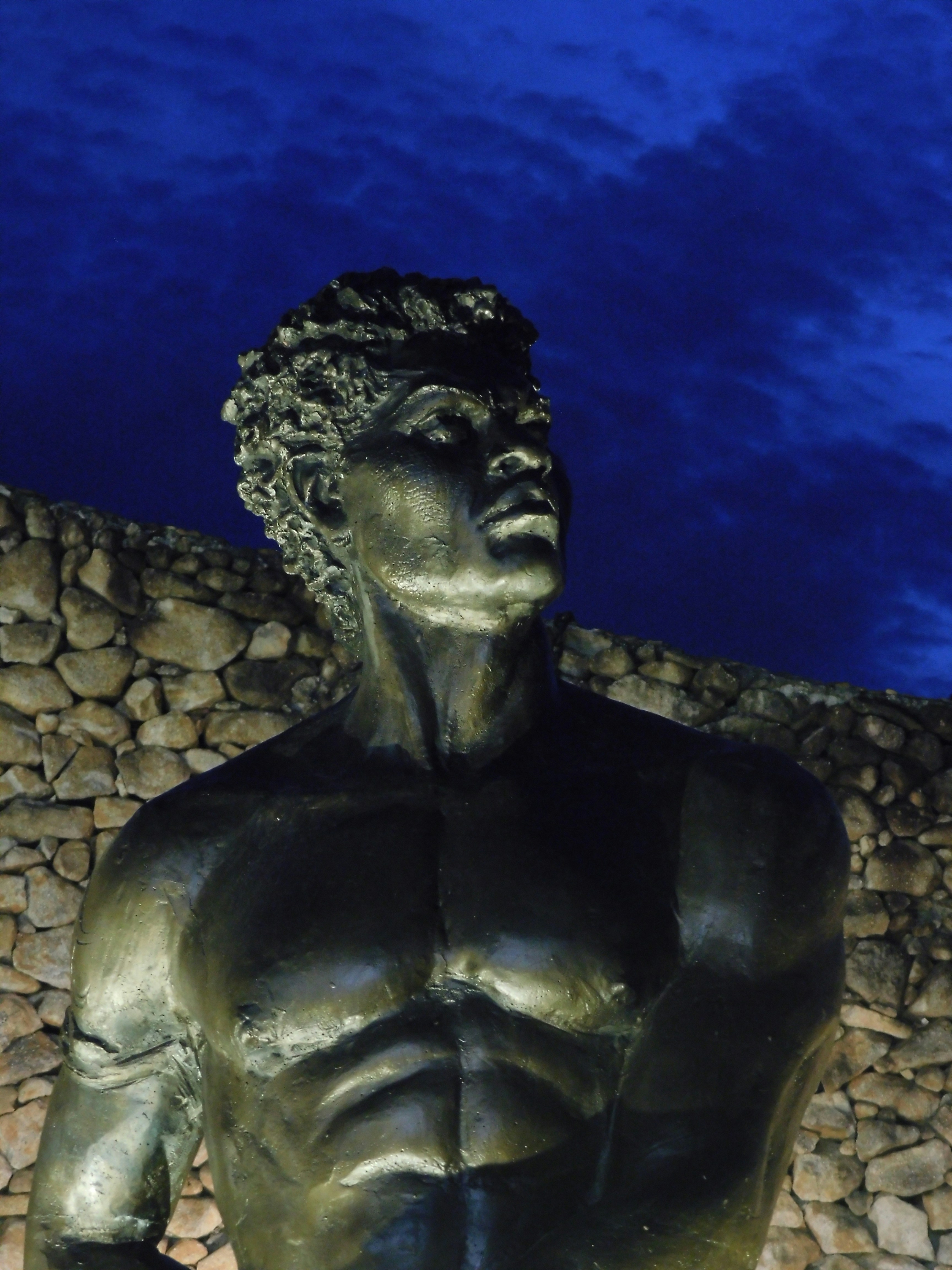 Uma estátua de um homem em pé na frente de uma parede