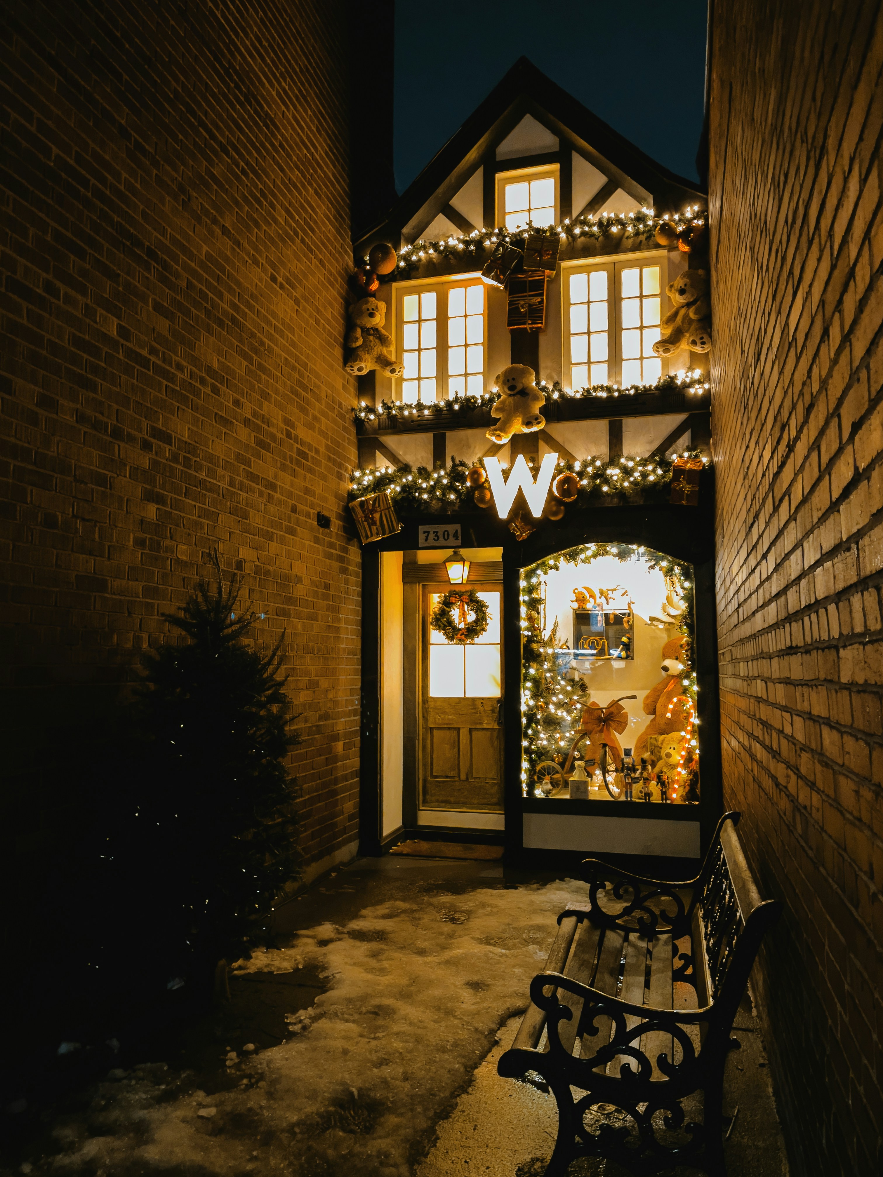 Warm inviting small town storefront on a snowy winter street, cozy interior lighting visible through large windows, small business atmosphere