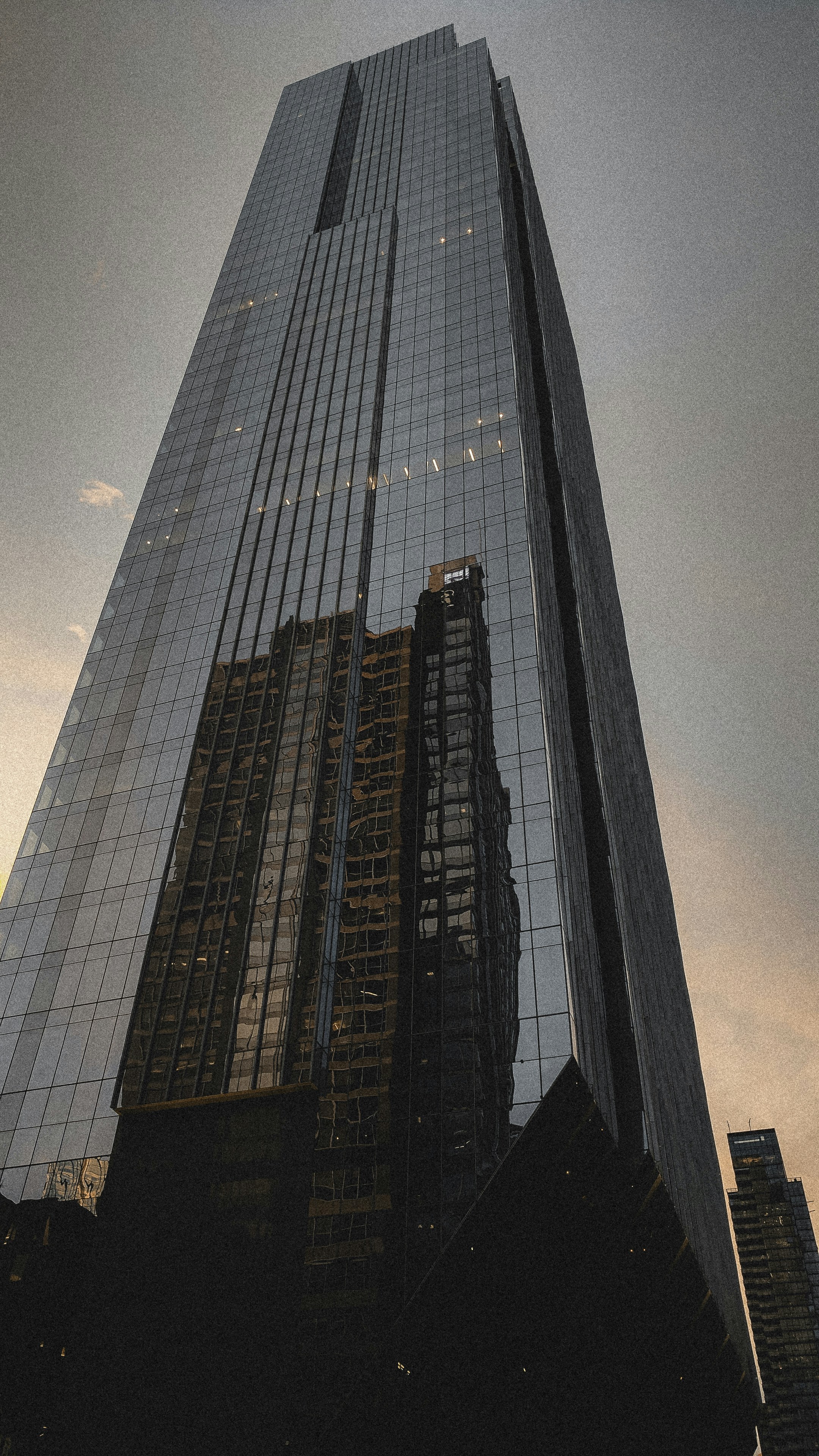 Modern glass office tower at night, reflective facade, dark sky, dramatic low-key lighting