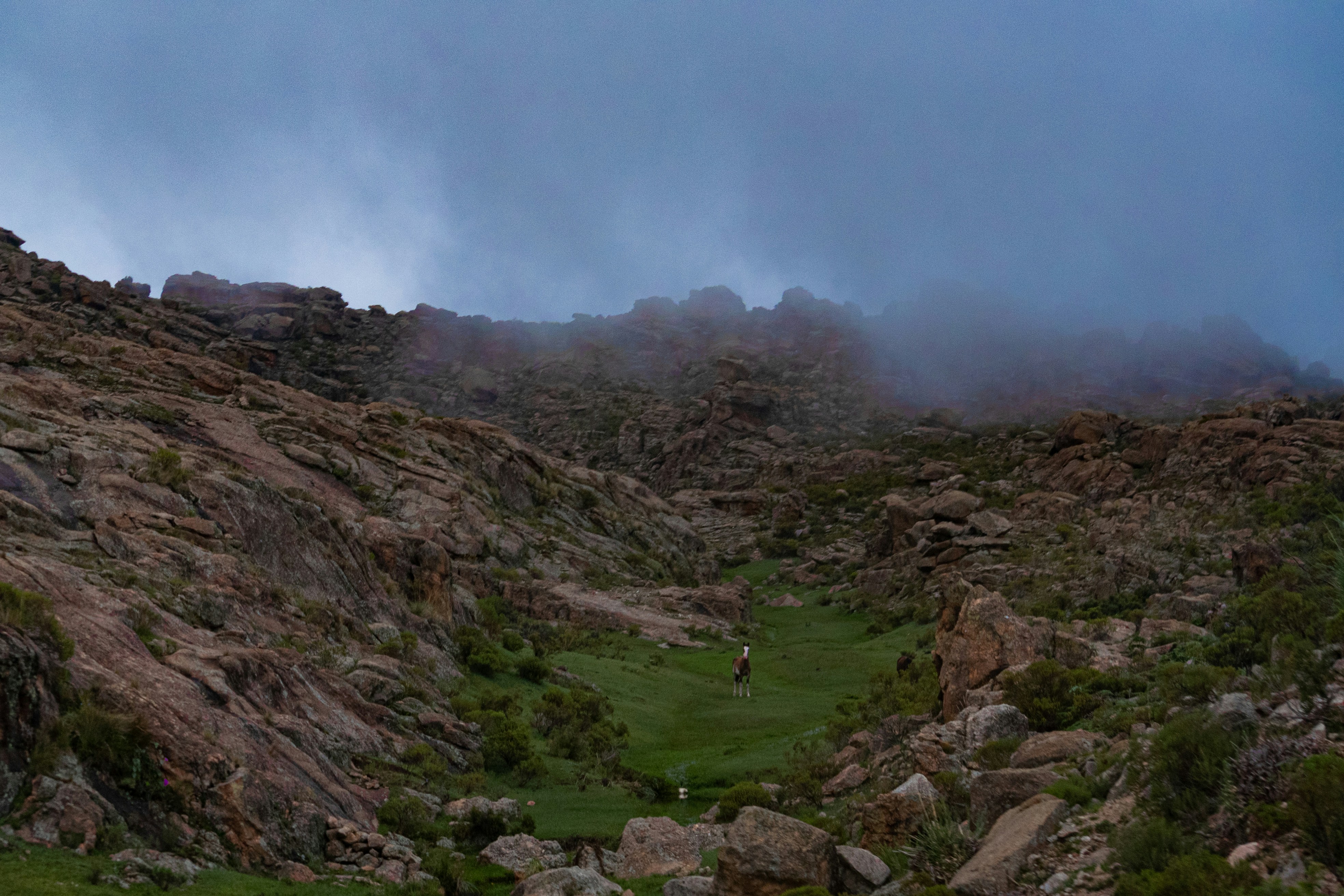 A hill with a grassy field below it on a cloudy day