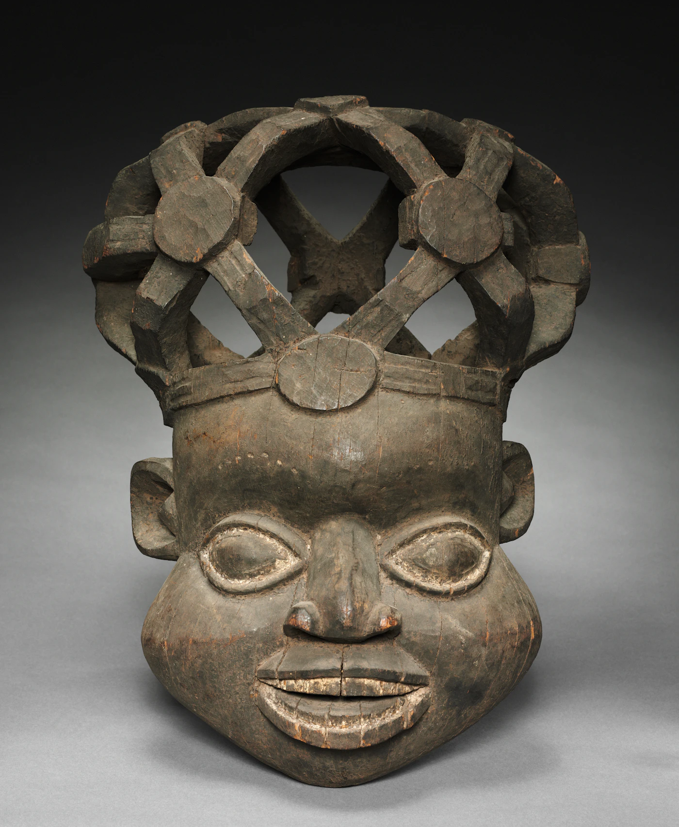 An aged wooden tribal mask with an elaborate carved headdress