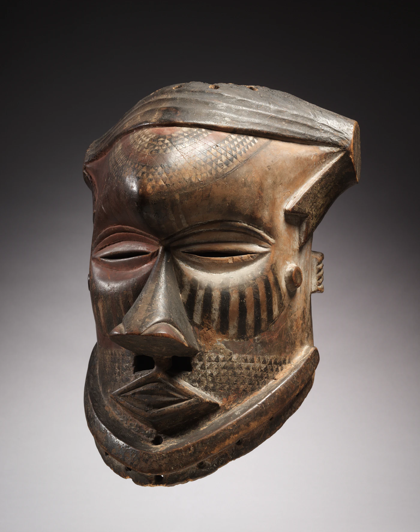 A carved wooden tribal mask with intricate surface detail