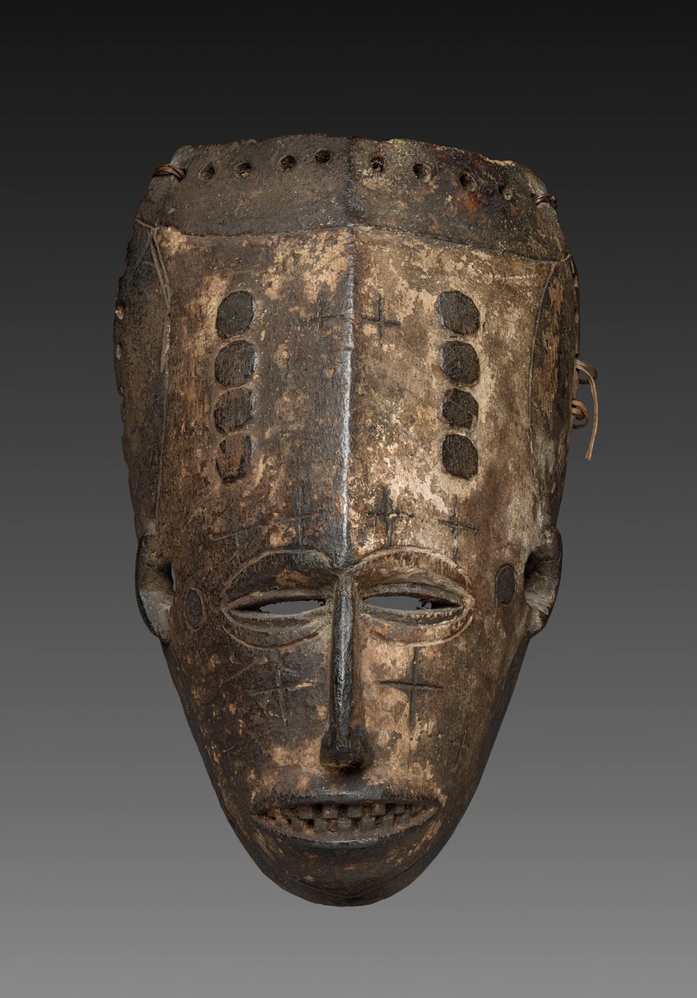 An aged carved wooden mask with intricate weathered markings