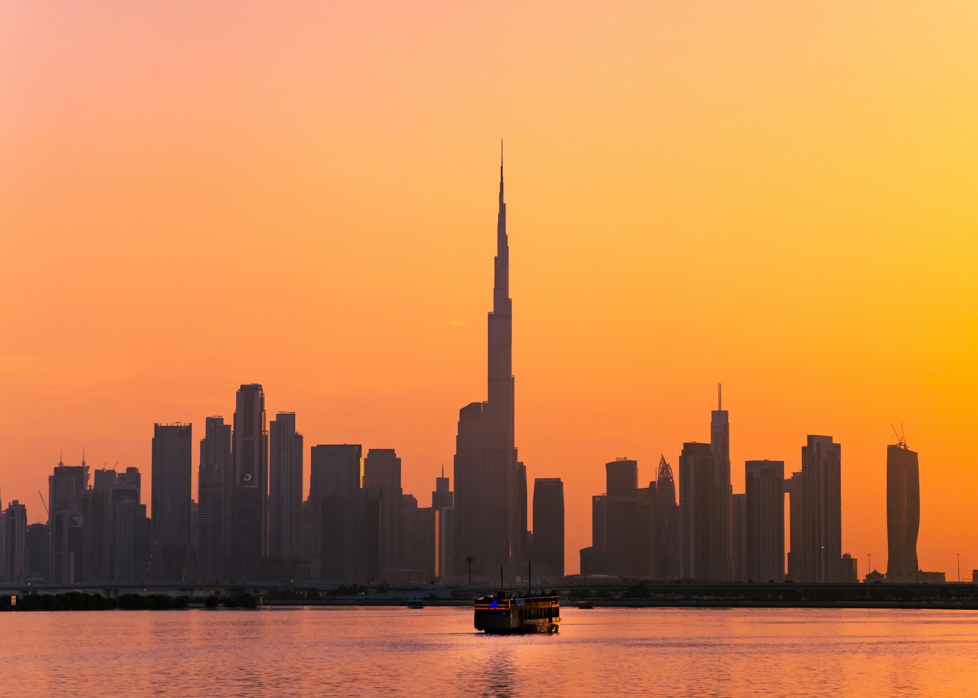 Dubai skyline at twilight from above, dramatic shadows on desert, deep blue sky, imposing architectural forms