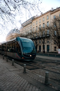 A train traveling down a street next to tall buildings