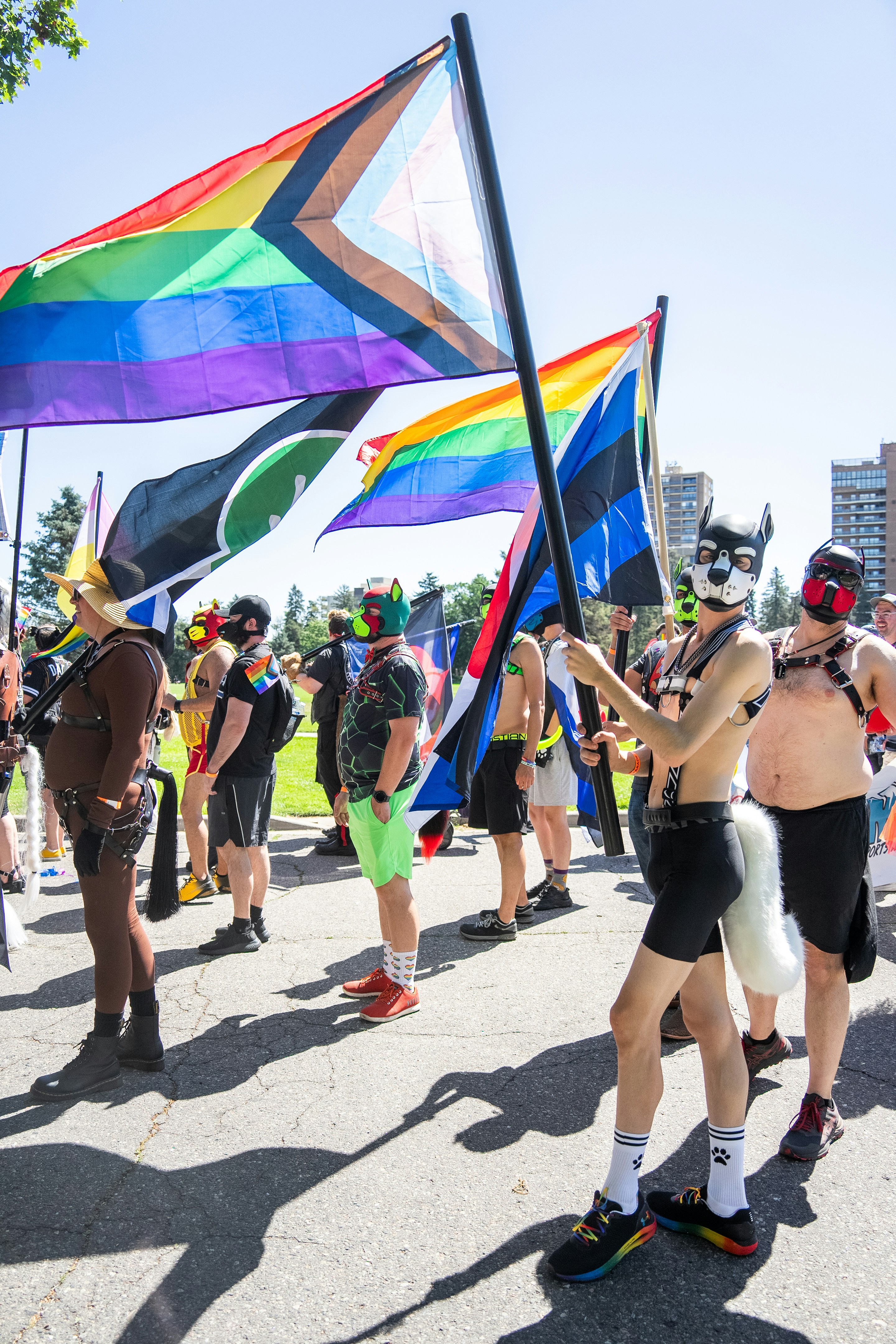 Festival goers in colorful outfits at outdoor pride celebration with rainbow flags