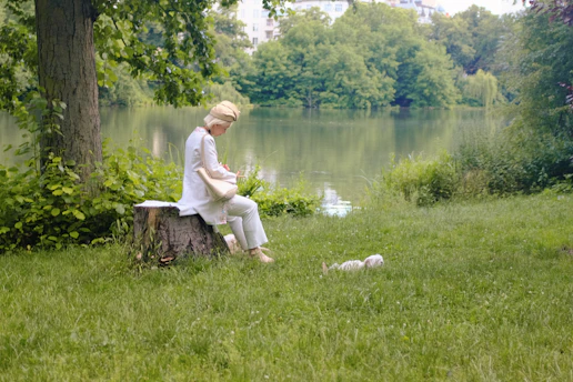 A man sitting on a tree stump next to a lake