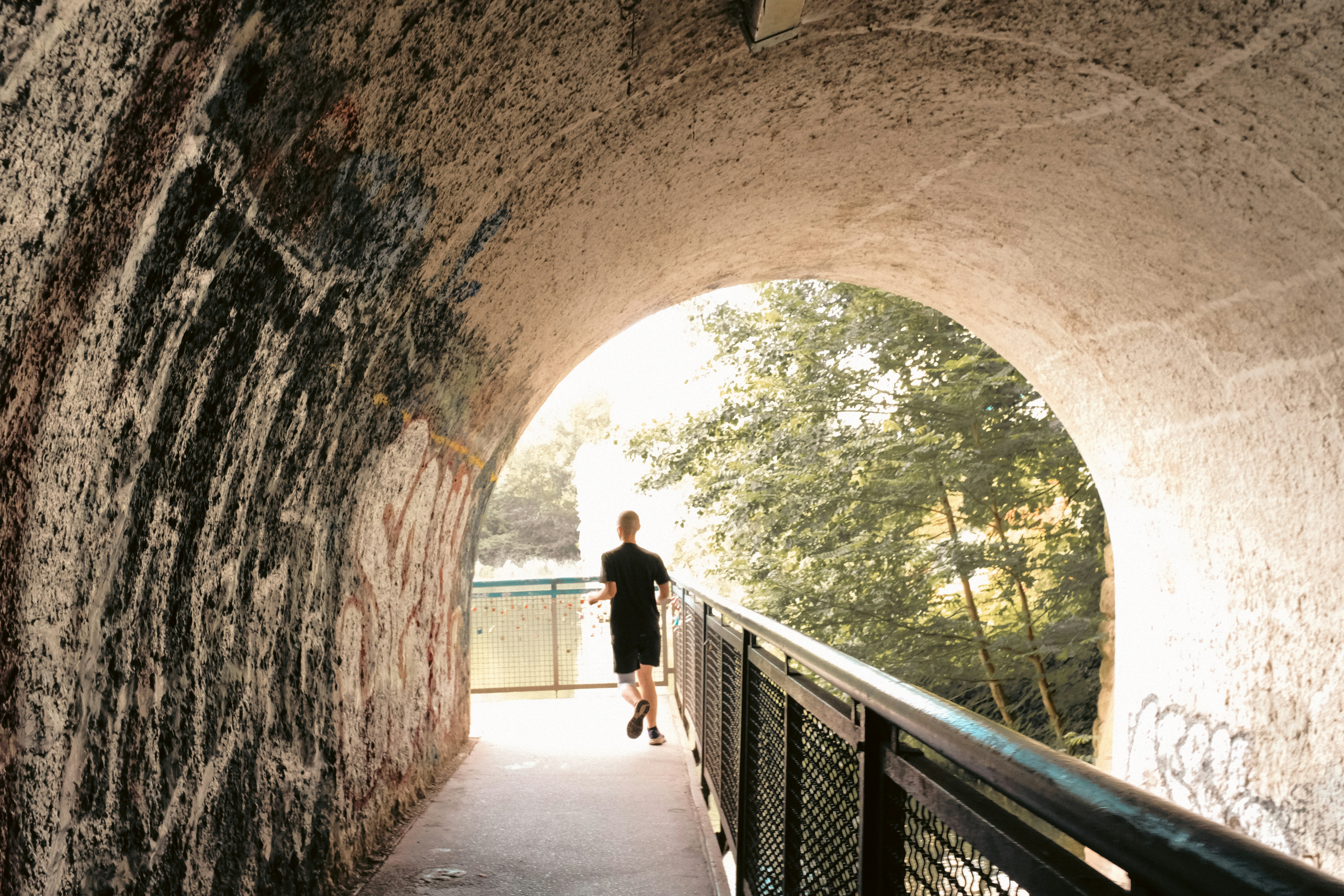 A man walking through a tunnel on a bridge