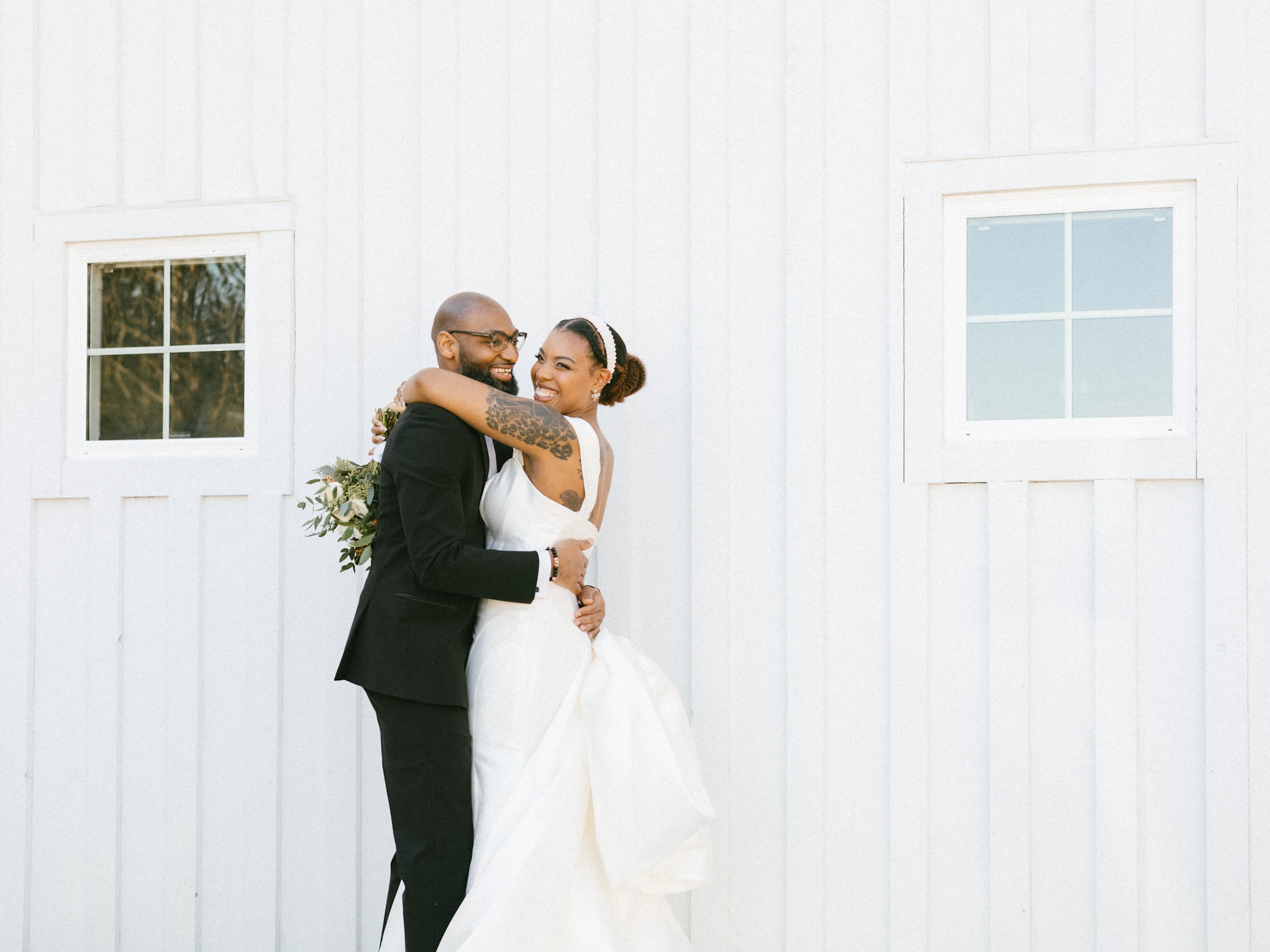 A bride and groom standing in front of a white building
