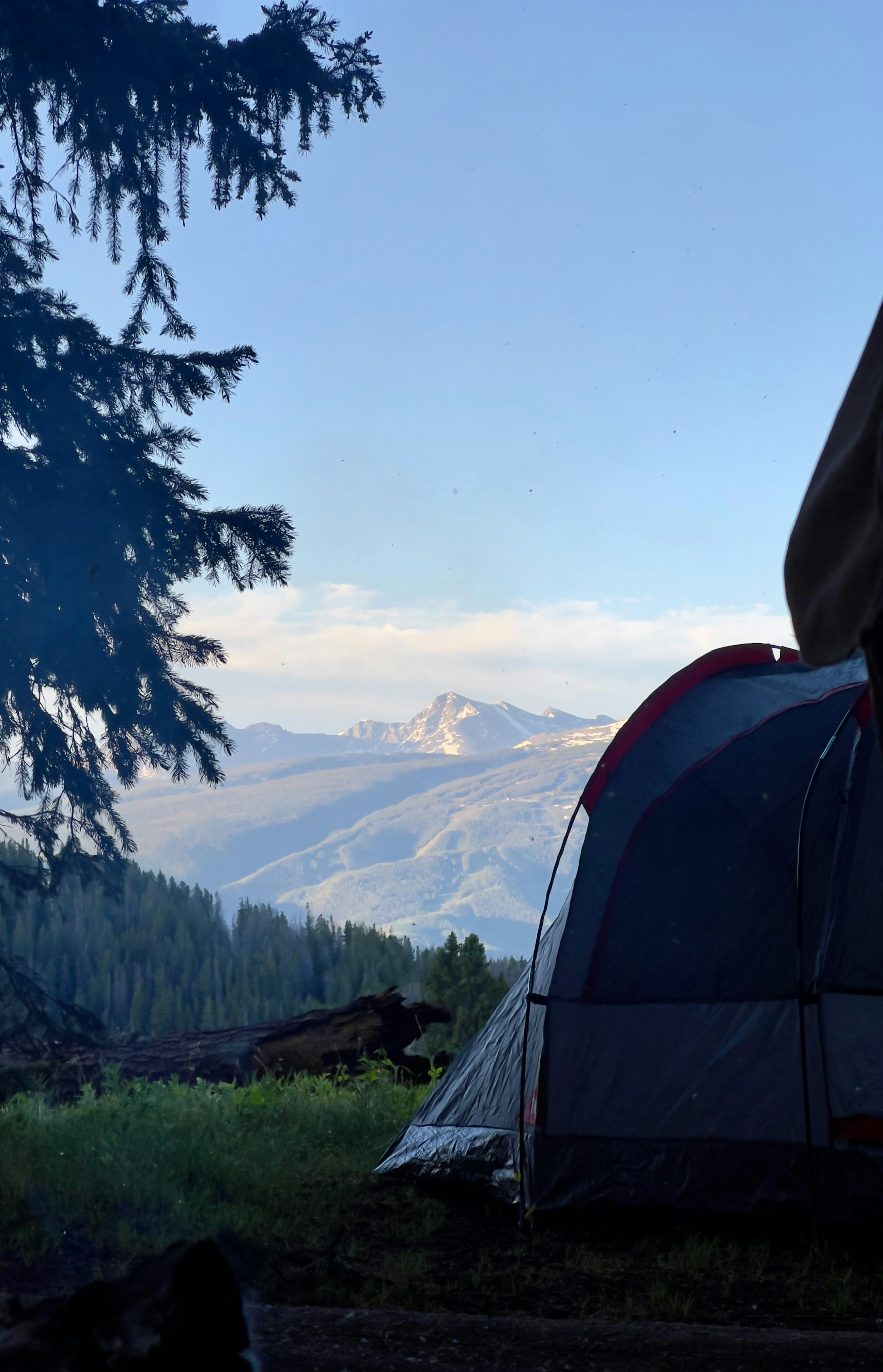 A tent pitched up in a field with mountains in the background