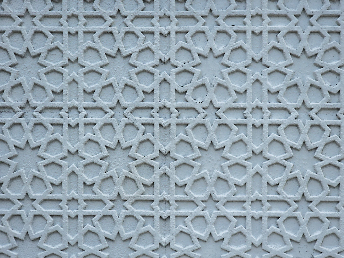 White wall carved with an interlocking Islamic geometric pattern
