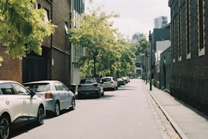 A city street lined with parked cars next to tall buildings