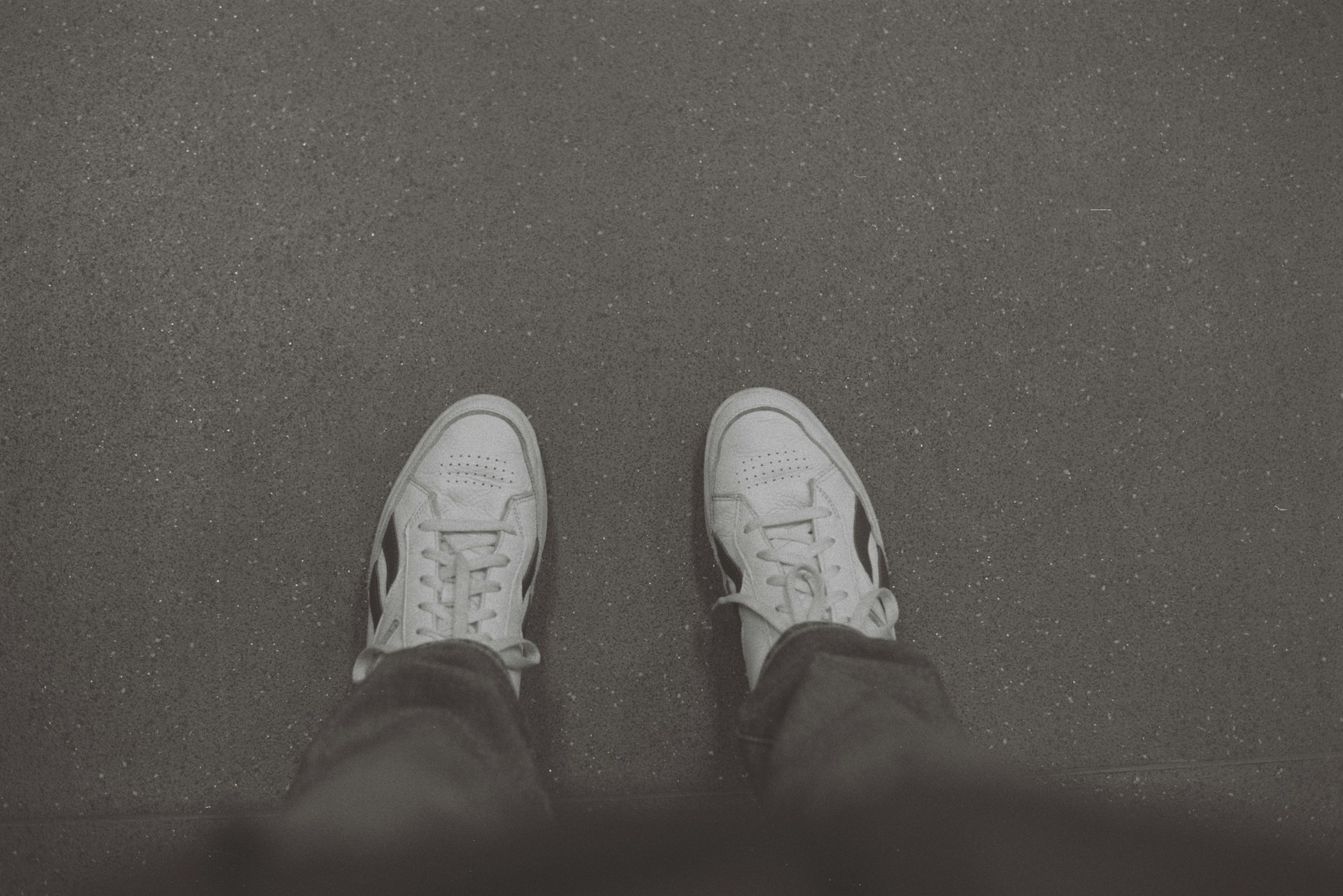 A pair of white shoes sitting on top of a black floor